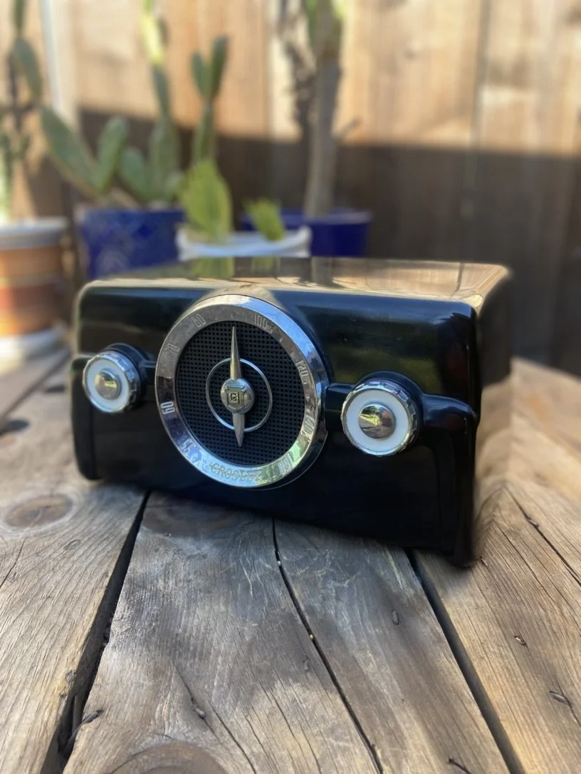 Vintage Crosley radio on a wooden table with potted plants in the background.