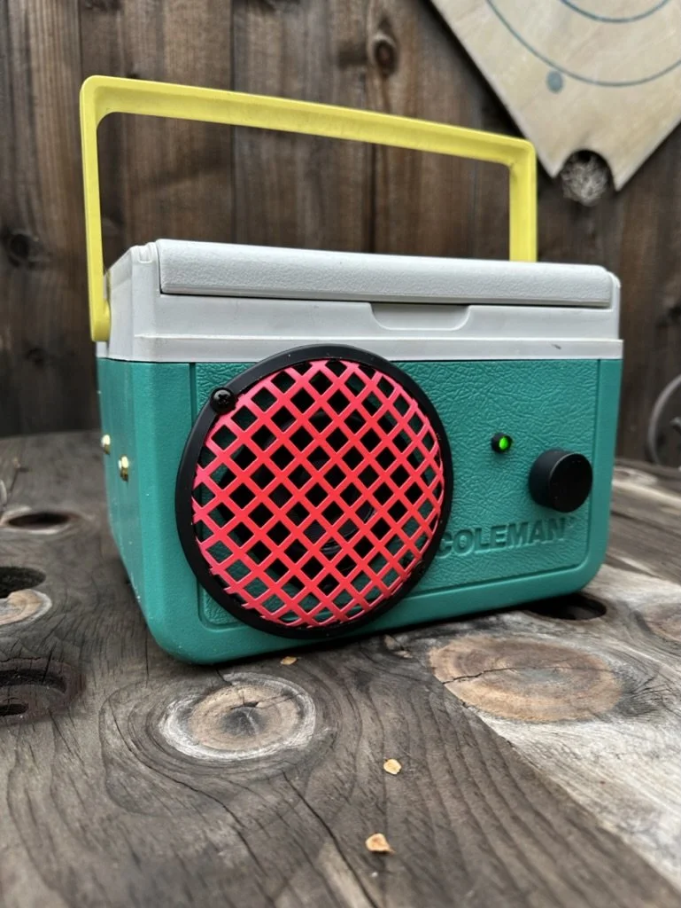 Vintage portable radio with blue body and yellow handle on a wooden surface