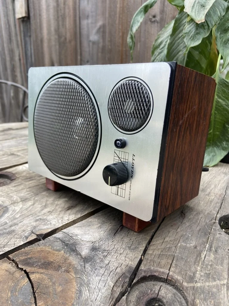 Vintage Lloyd's speaker system with wood finish on a wooden surface, outdoors.