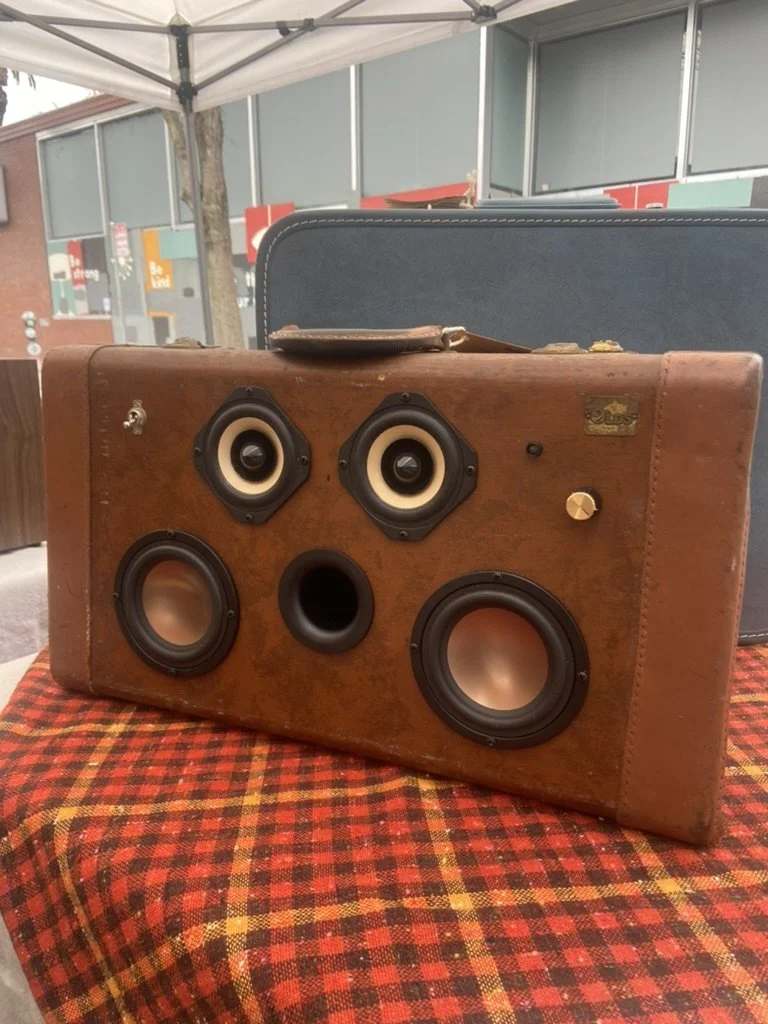 Vintage-style suitcase converted into a portable speaker system with multiple speakers embedded.