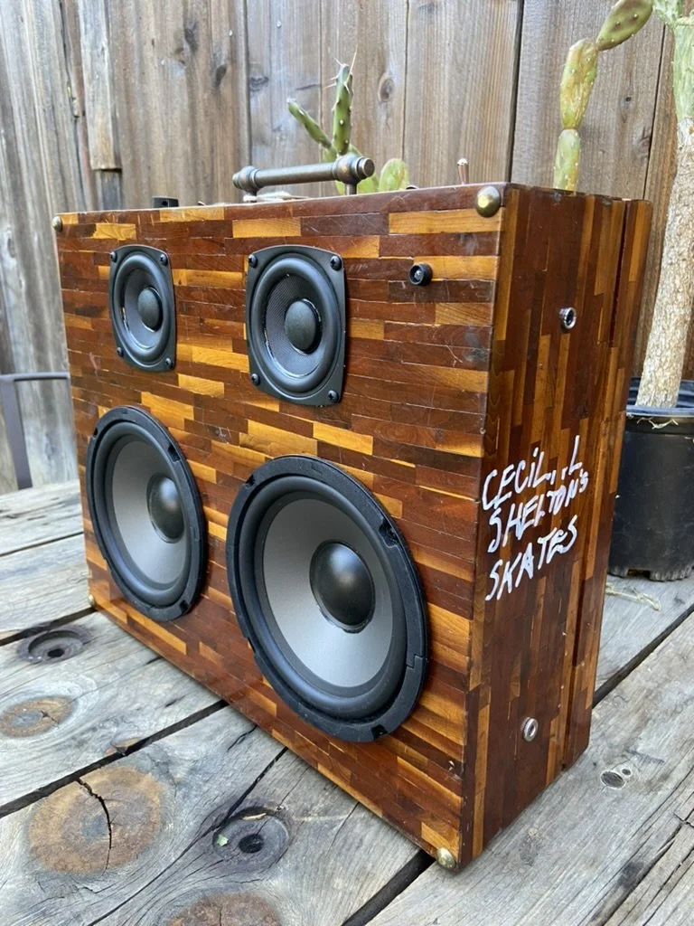Wooden portable speaker with multiple drivers on a wooden table, outdoor setting, with text 'Cecil Streetons Skate's' written on the side.