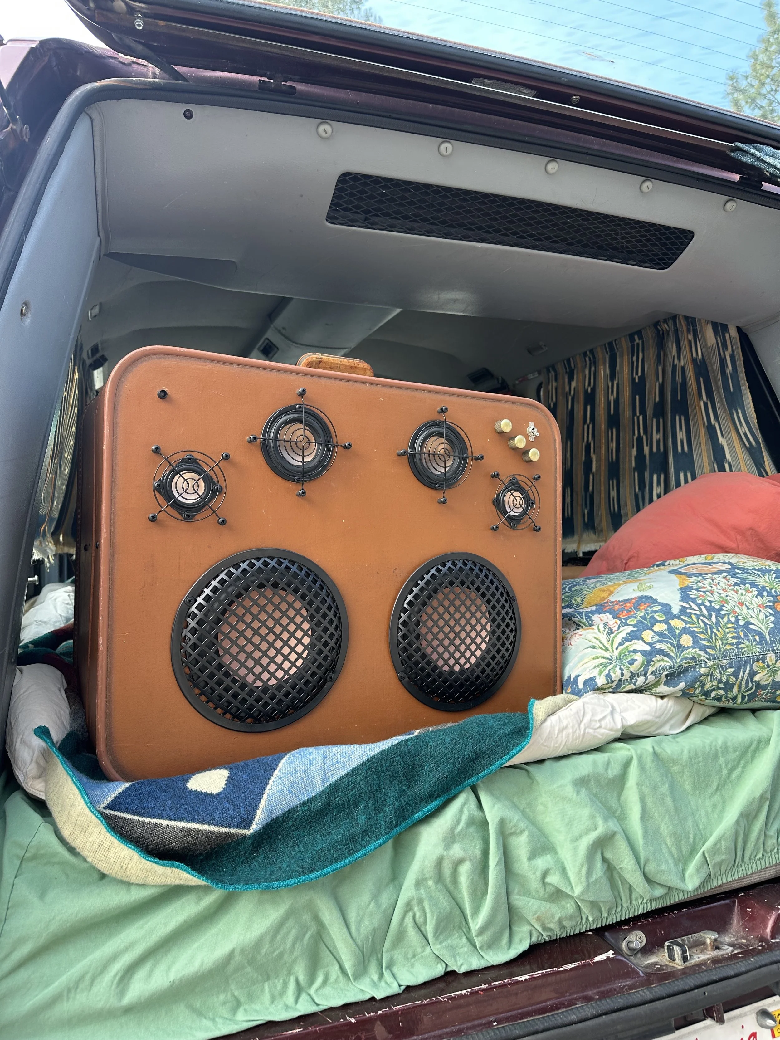 DIY stereo system in van trunk with bedding made of an accordion case. Custom peice