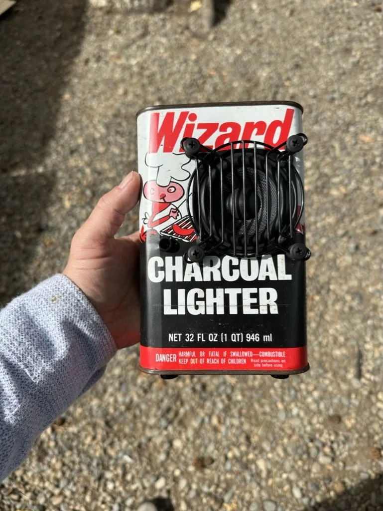 Hand holding a modified charcoal lighter container with a speaker attached.