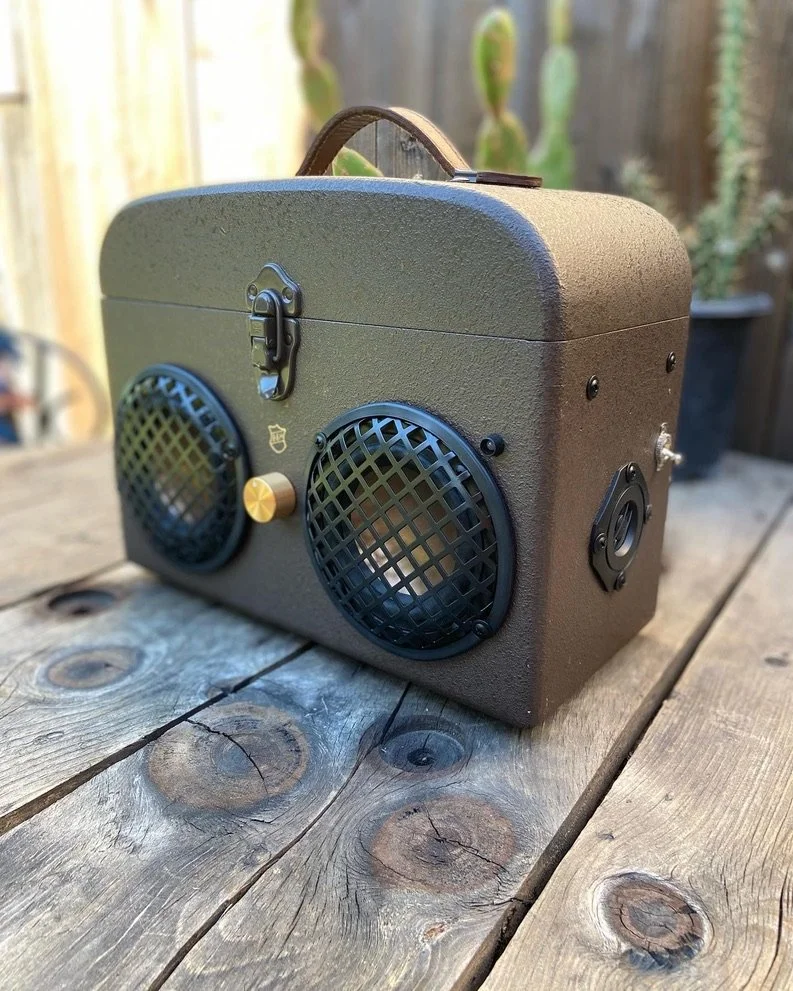 Vintage-style portable speaker with two round grills on a wooden table