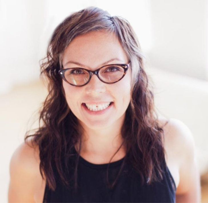 A white woman with black glasses smiles warmly