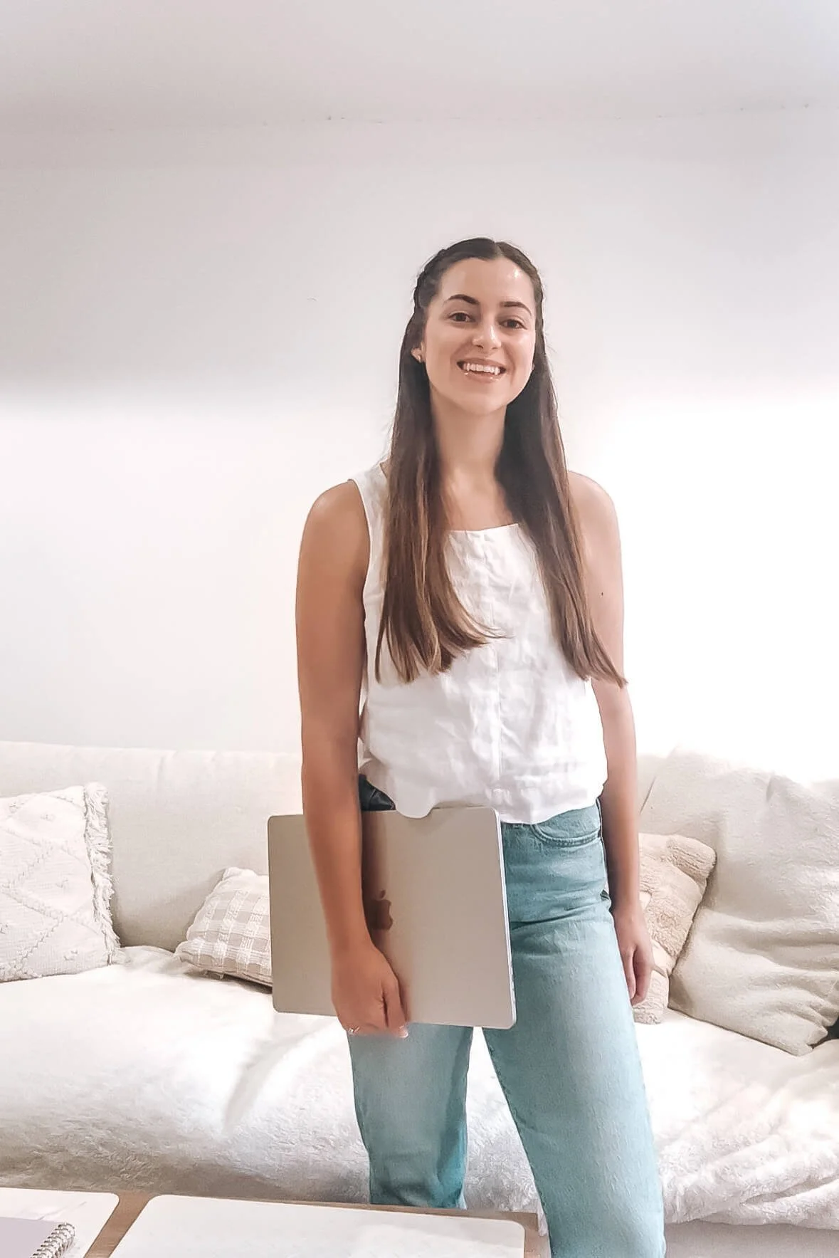 Web designer, Sophie Wuthrich, with a linen white top and casual light blu jeans smiling and holding macbook