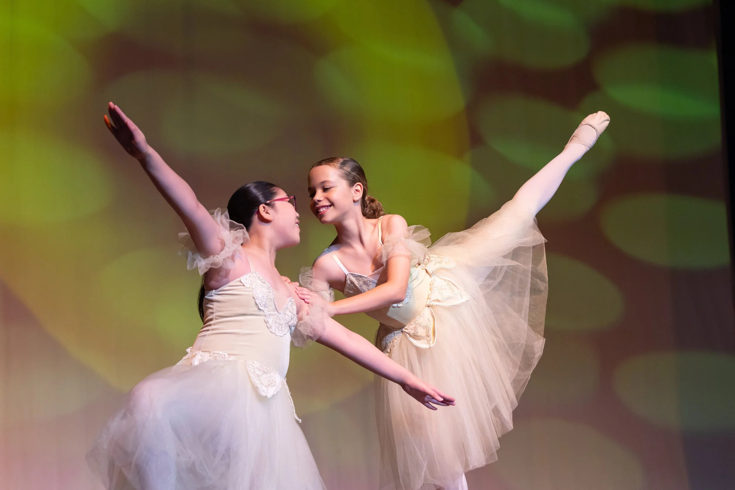 Smiling child in pink dance costume with outstretched arms on stage
