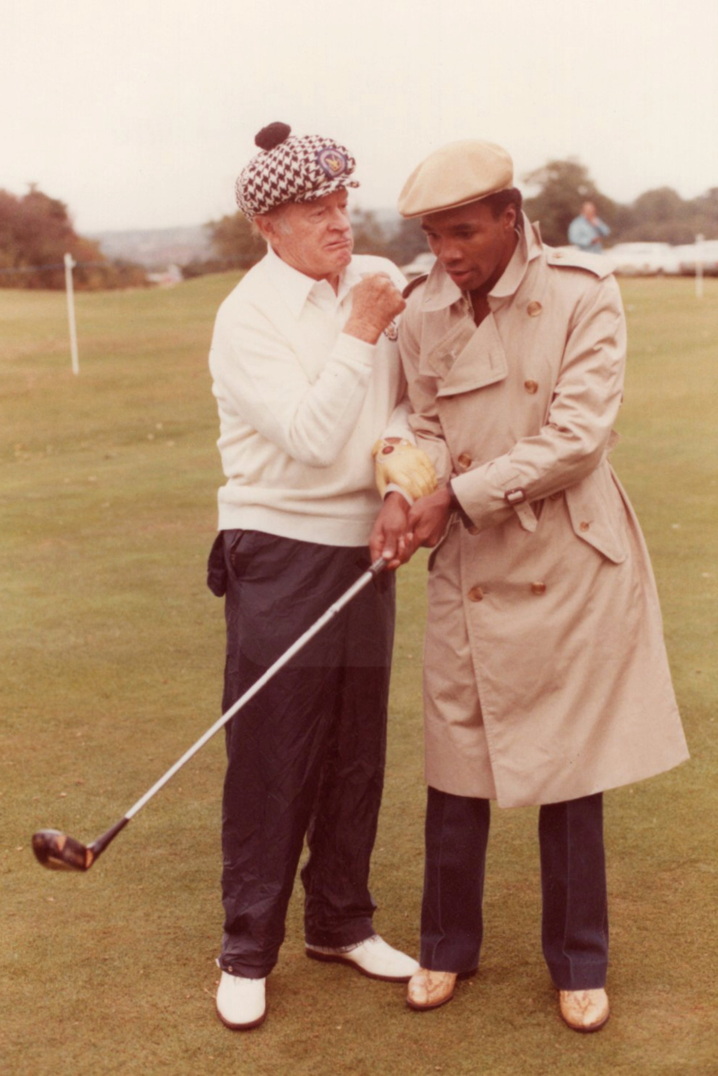 Bob Hope playfully puts his fist up to Sugar Ray Leonard's face at the Bob Hope Classic Celebrity Pro-Am Golf Tournament. Shot by James Anderson Jr. Moor Park Golf Club, Hertfordshire, London, September 1982.