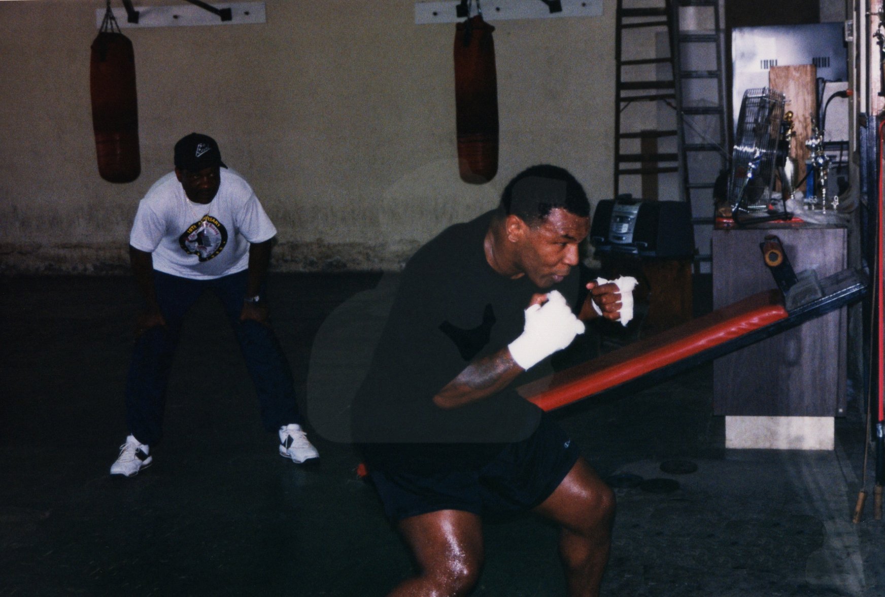 Mike Tyson practices his trademark "Peek-A-Boo" style in the mirror during training as his coach Tommy Brooks looks on. Las Vegas, NV, July 31st, 1999