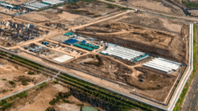 Aerial view of a large construction site with multiple buildings, roads, and cleared land.