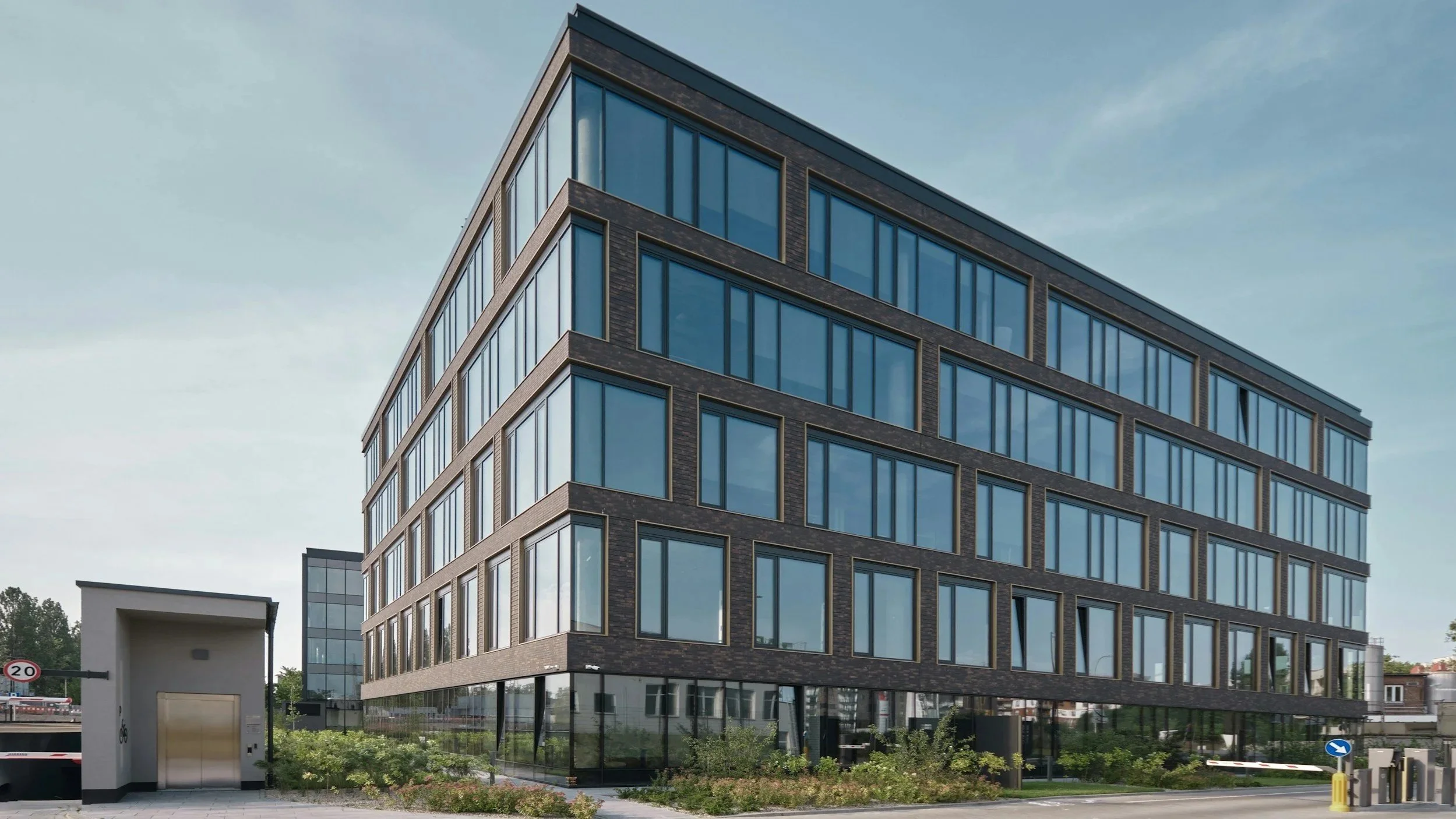 Modern multi-story building with large glass windows and dark brick exterior.