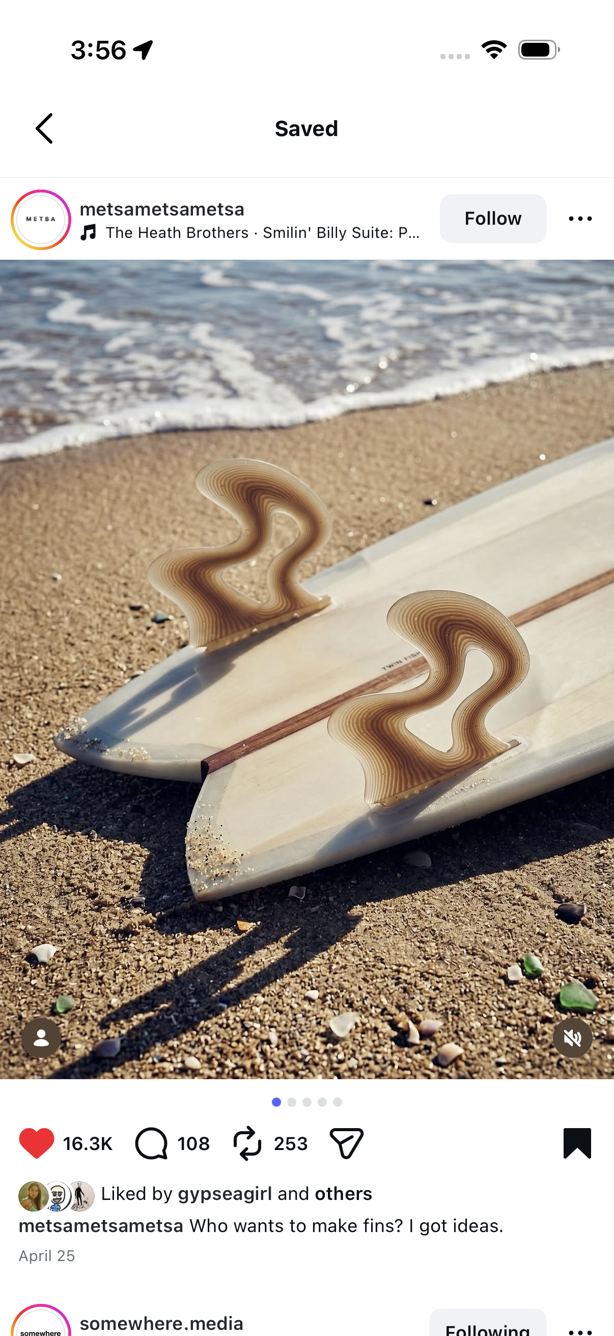 Two surfboards lying on sandy beach with ocean waves in background, featuring creatively shaped fins.