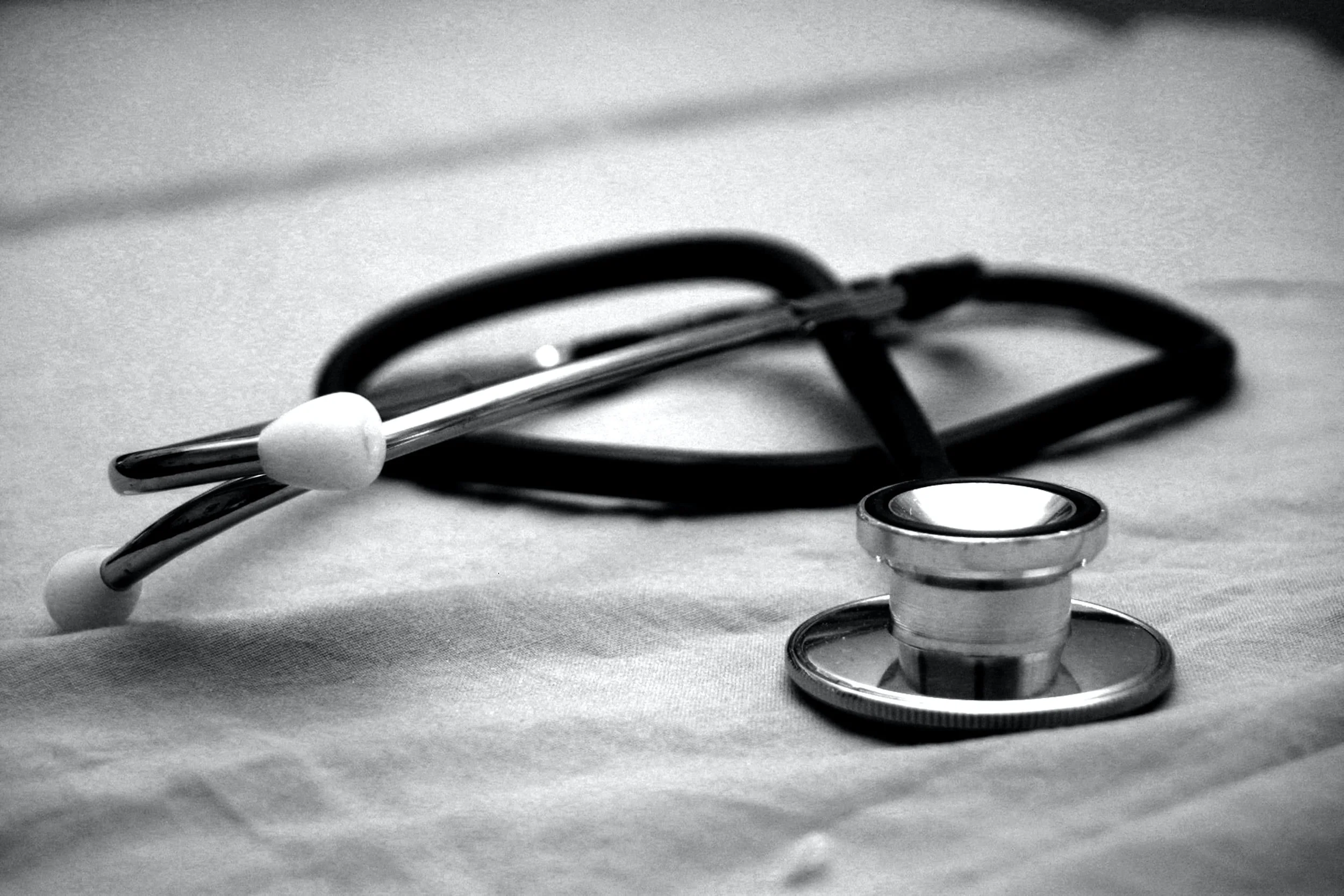 Black and white image of stethoscope on white sheet