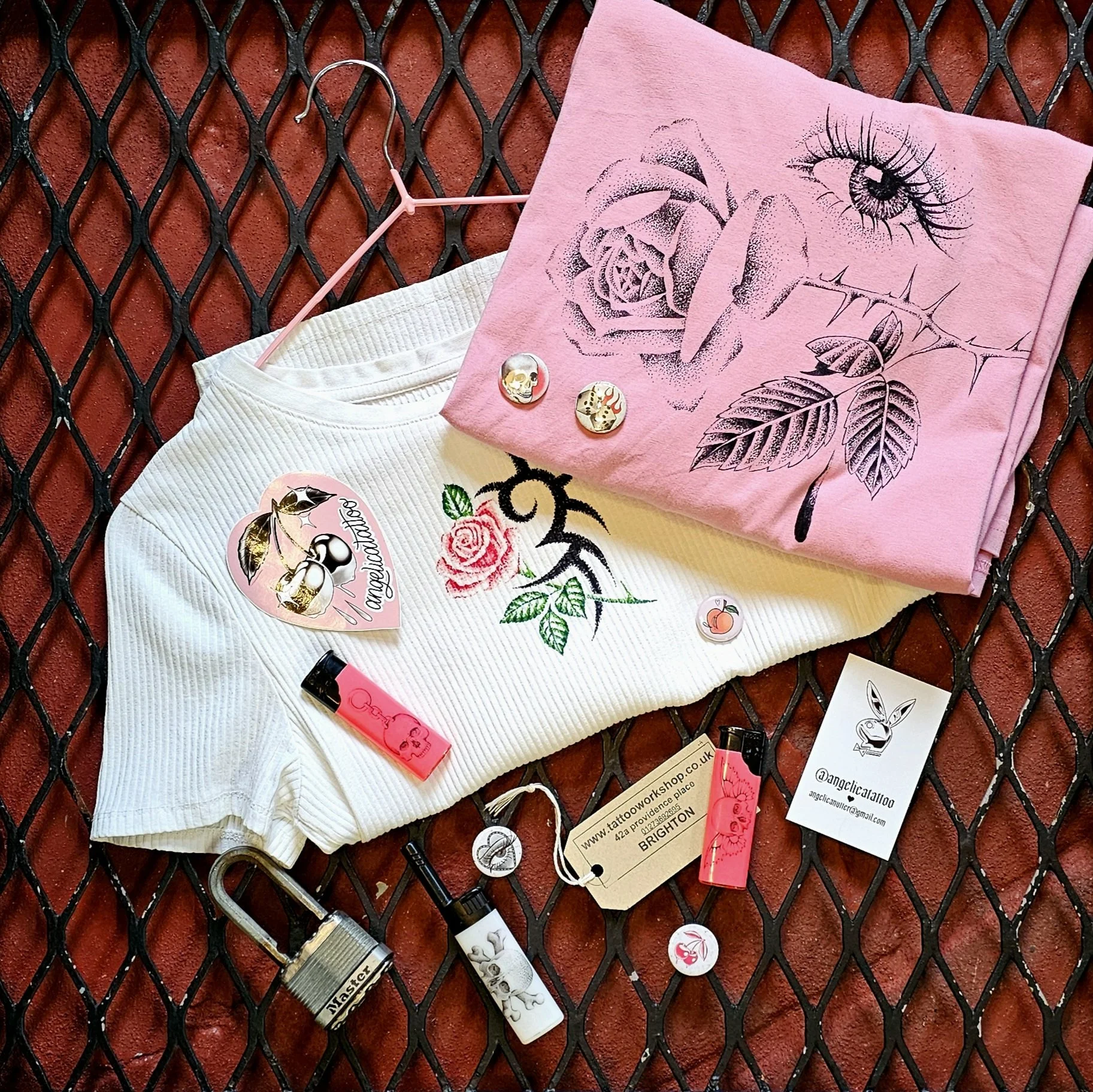 Pink and white clothing and accessories with floral and eye designs on a black metal surface.