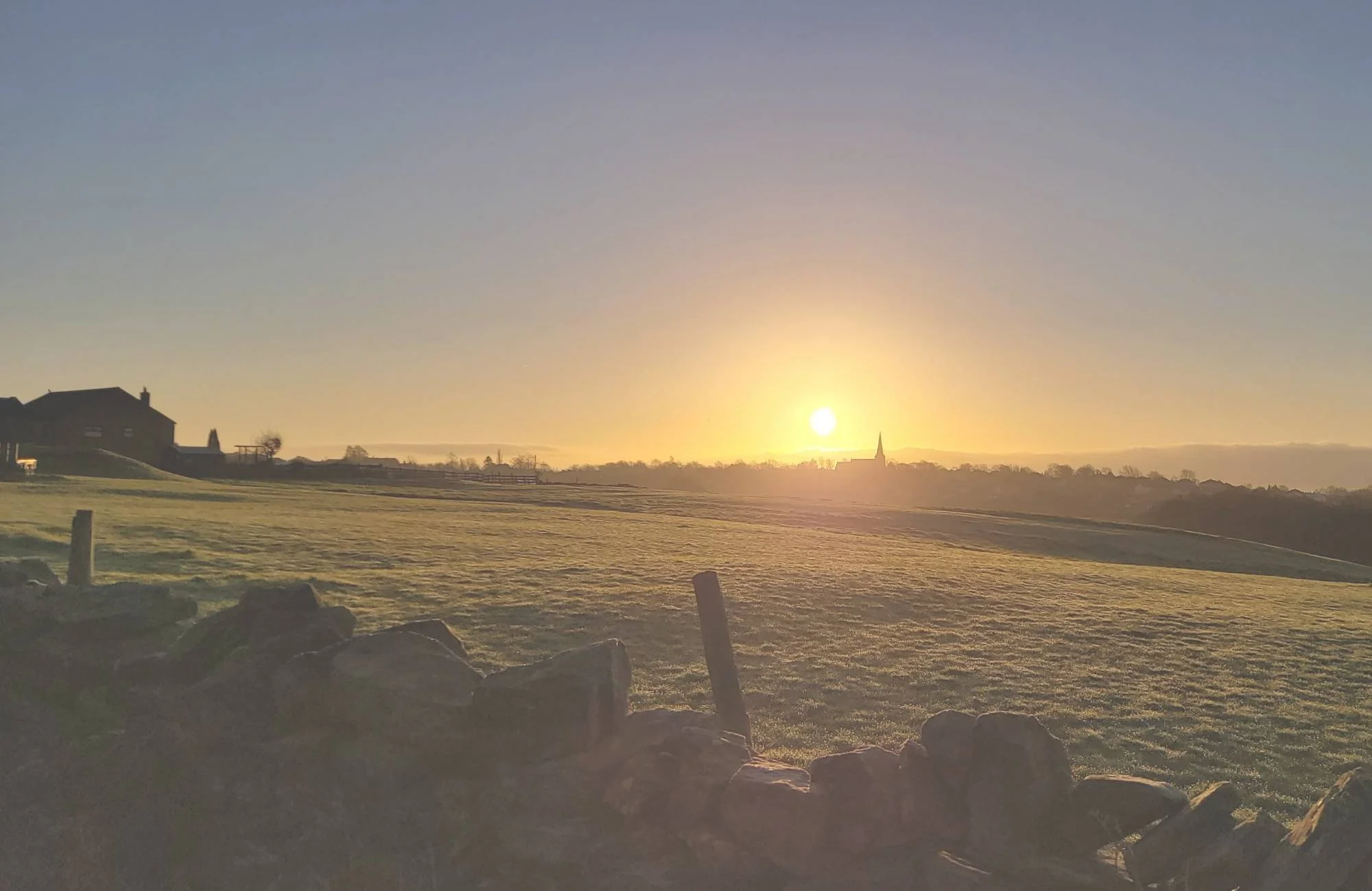 Peaceful sunrise over farmhouse and open fields representing a calm and supportive start to the year
