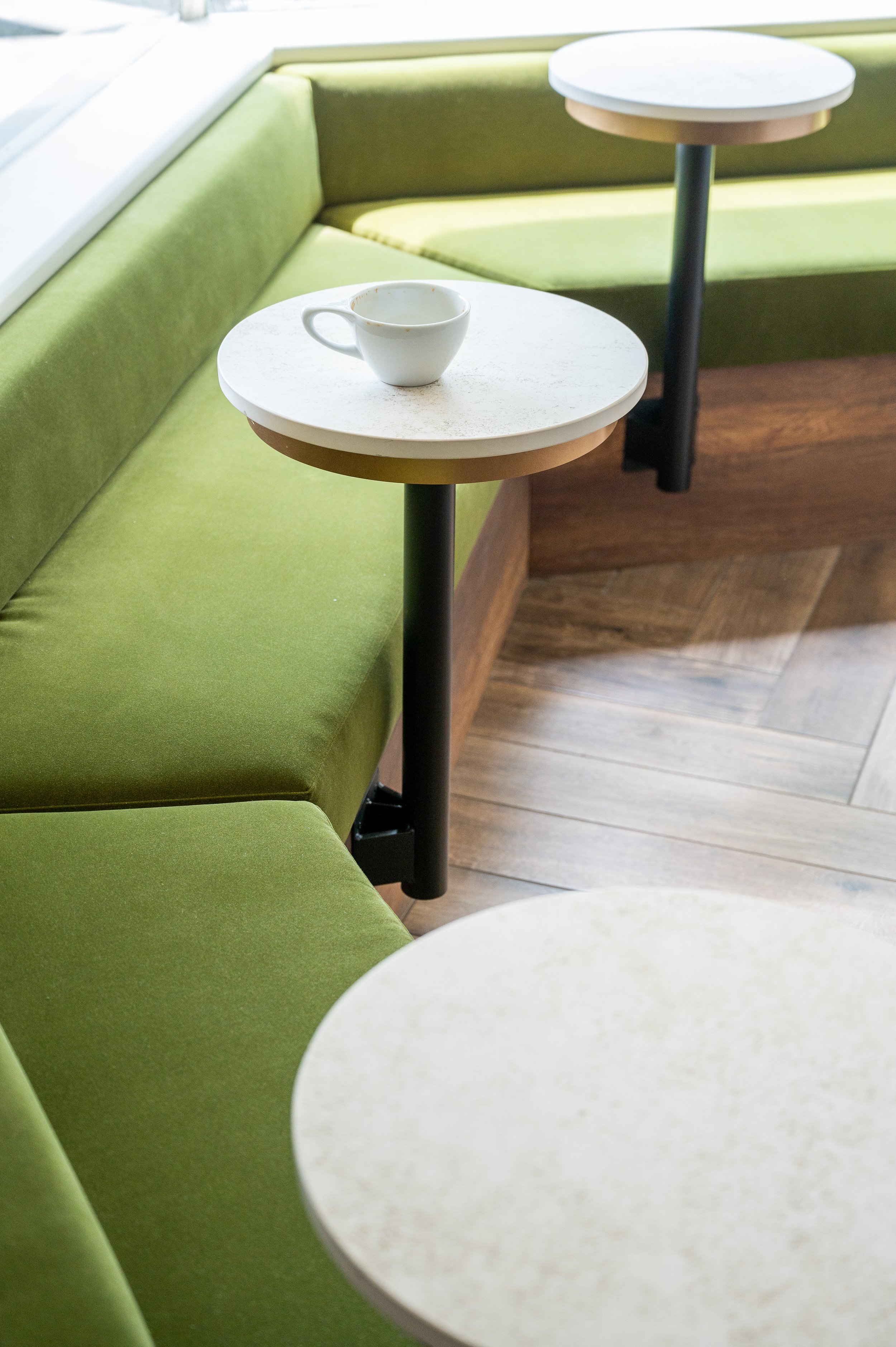 This chic café interior boasts sleek wooden shelves and curved lighting with greenery, set against a backdrop of soft green tiles. The combination of natural wood and modern design creates a warm, inviting atmosphere for coffee enthusiasts.
Discover 