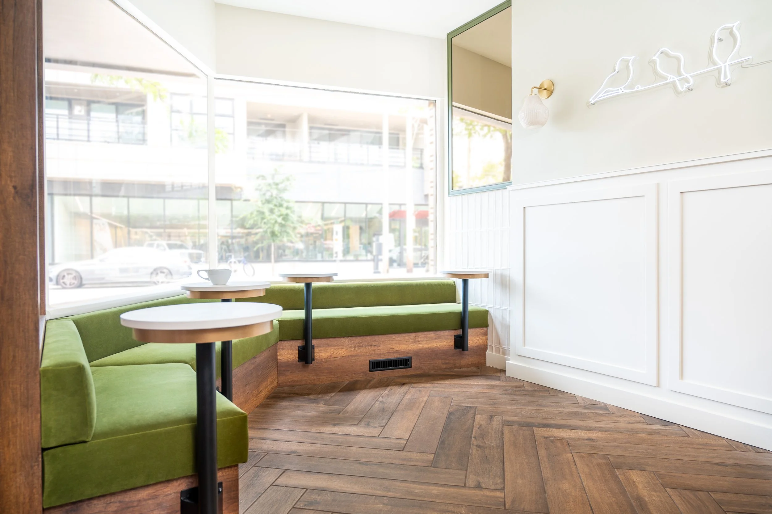 This chic café interior boasts sleek wooden shelves and curved lighting with greenery, set against a backdrop of soft green tiles. The combination of natural wood and modern design creates a warm, inviting atmosphere for coffee enthusiasts.
Discover 