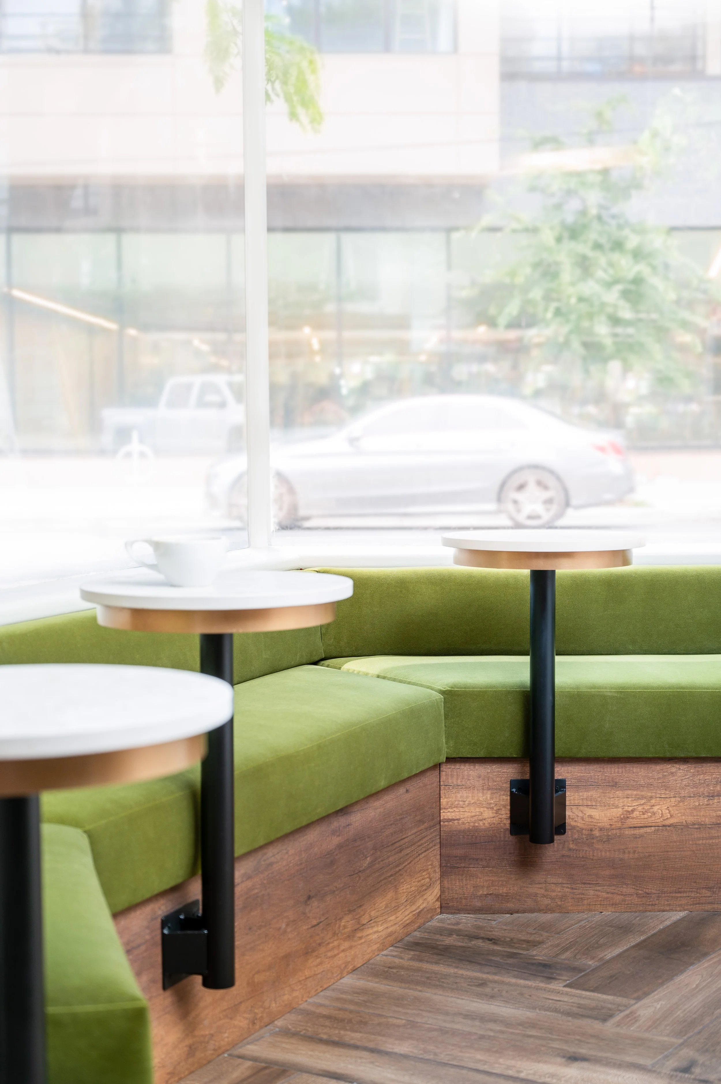 This chic café interior boasts sleek wooden shelves and curved lighting with greenery, set against a backdrop of soft green tiles. The combination of natural wood and modern design creates a warm, inviting atmosphere for coffee enthusiasts.
Discover 