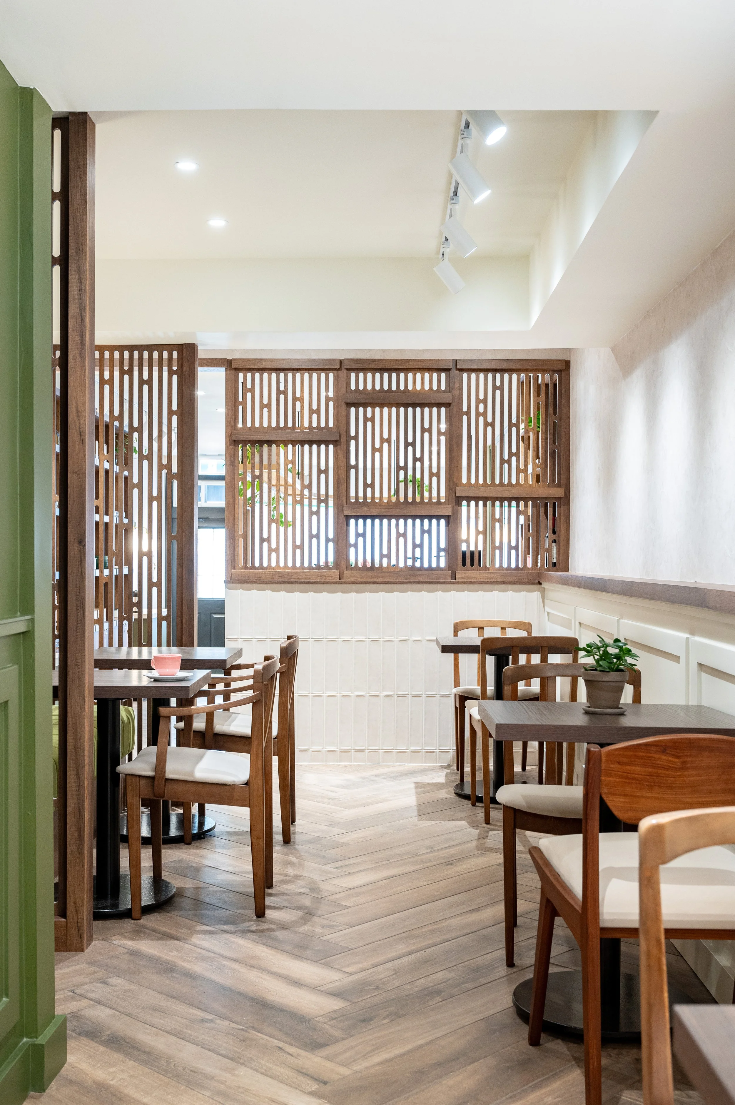 This chic café interior boasts sleek wooden shelves and curved lighting with greenery, set against a backdrop of soft green tiles. The combination of natural wood and modern design creates a warm, inviting atmosphere for coffee enthusiasts.
Discover 