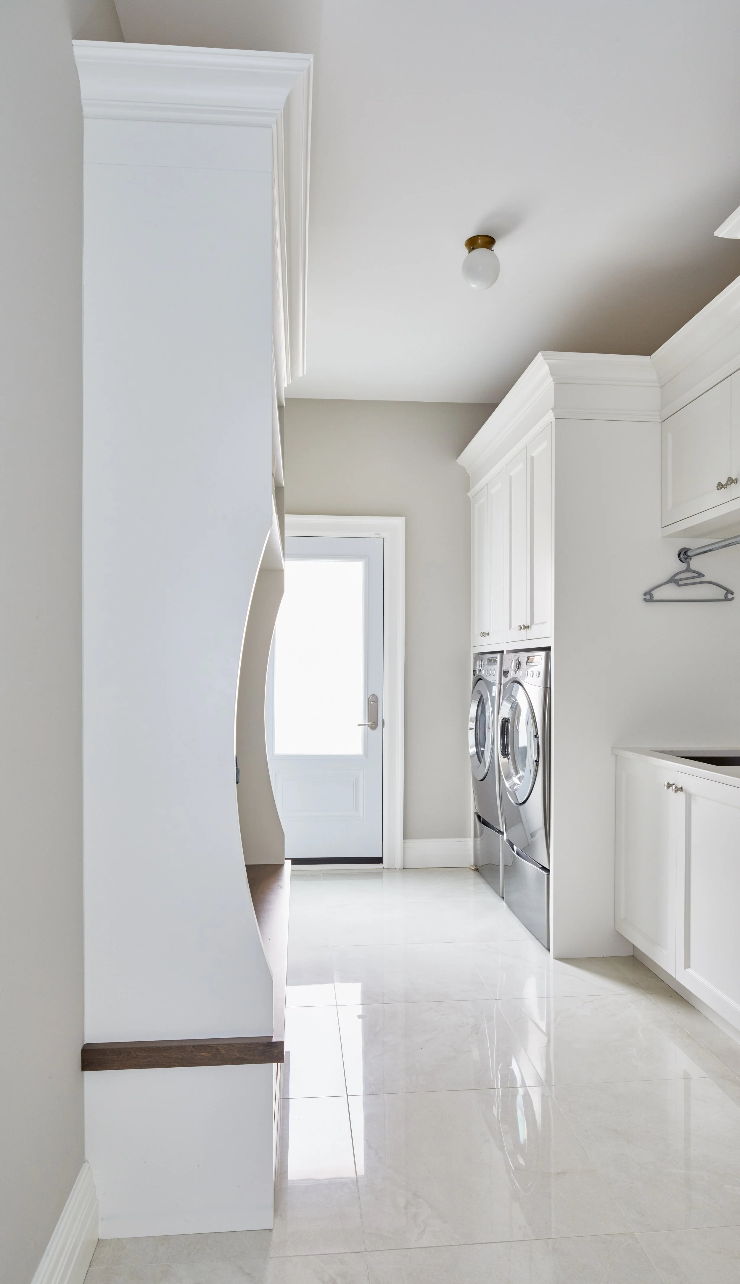 A laundry room with white cabinets, a front door with a window, and a washer and dryer.