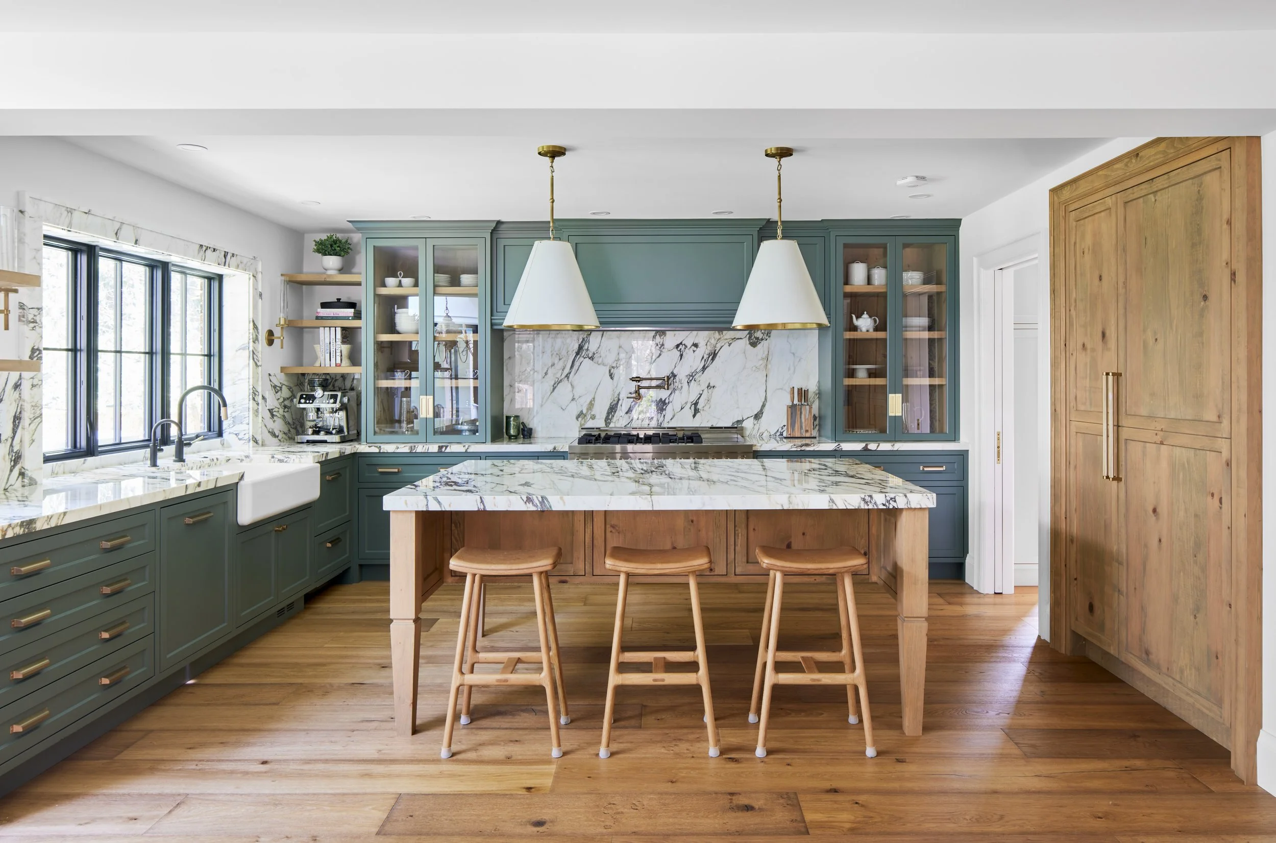 High-end custom modern kitchen in Mississauga, Oakville, and Toronto, Ontario. Features trends color for 2024, luxurious gold hardware, a marble countertop, an elegant kitchen sink, custom shelving with a pocket door, and efficient kitchen and drawer