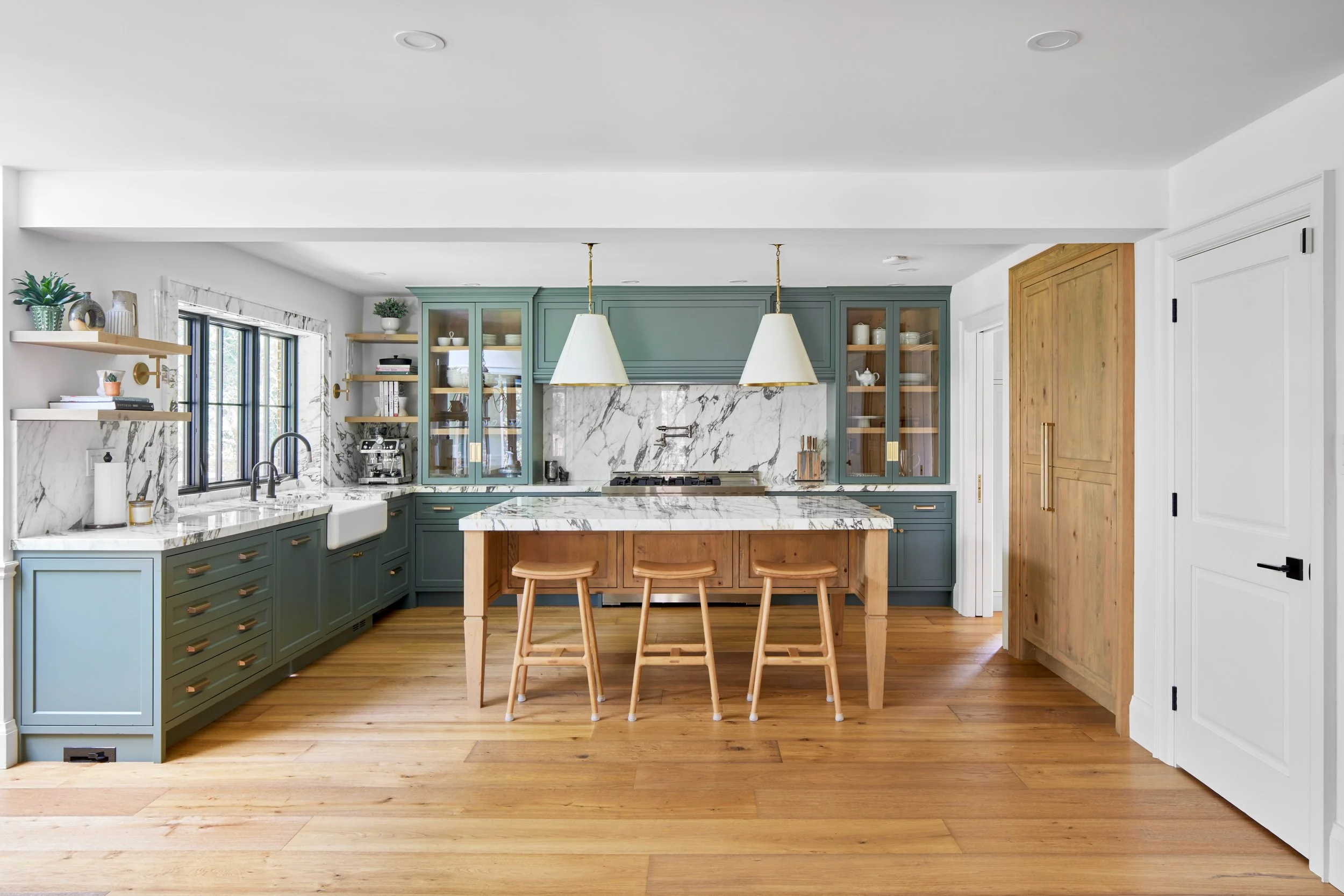 High-end custom modern kitchen in Mississauga, Oakville, and Toronto, Ontario. Features trends color for 2024, luxurious gold hardware, a marble countertop, an elegant kitchen sink, custom shelving with a pocket door, and efficient kitchen and drawer
