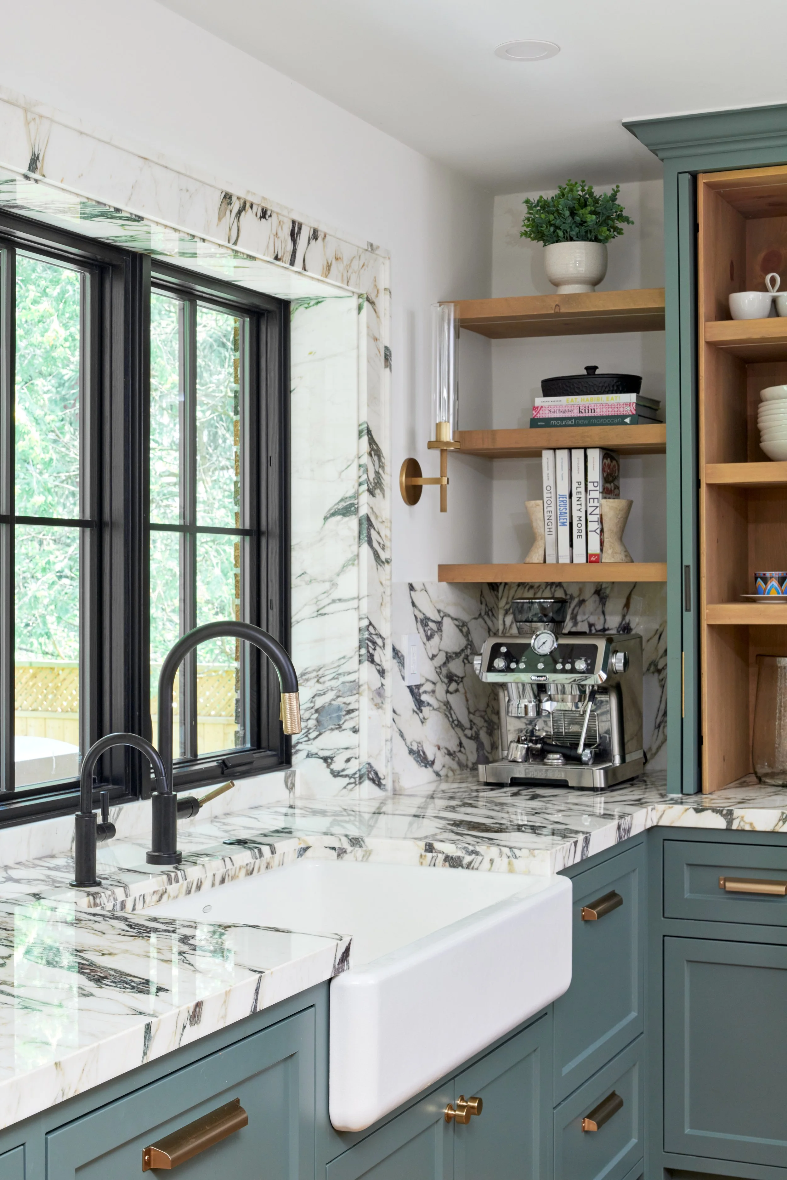 High-end custom modern kitchen in Mississauga, Oakville, and Toronto, Ontario. Features trends color for 2024, luxurious gold hardware, a marble countertop, an elegant kitchen sink, custom shelving with a pocket door, and efficient kitchen and drawer