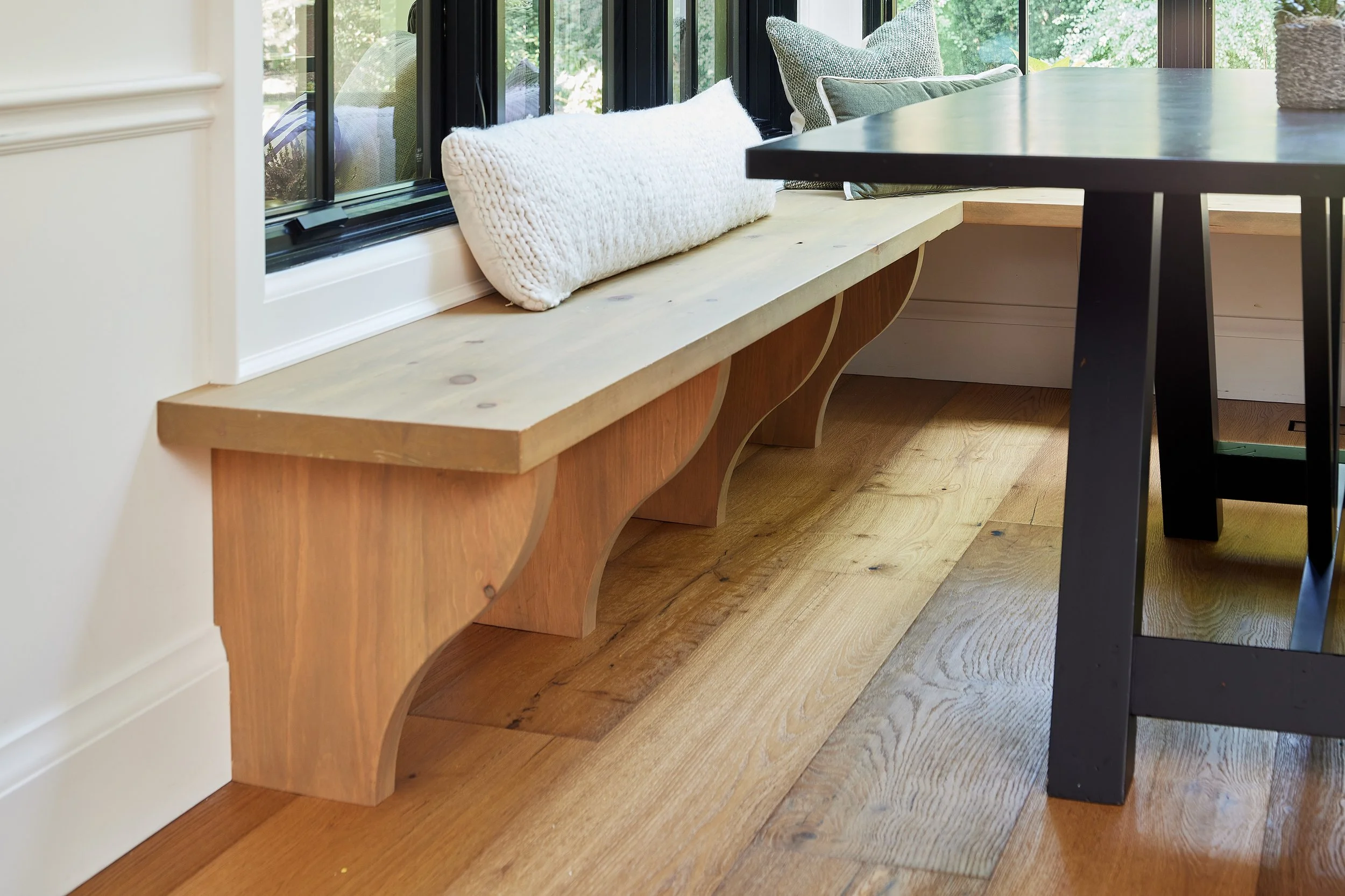 Window seating with modern open kitchen concept. Window bench designs and kitchen renovation near me. Custom dining table and furniture in matte black with open kitchen.  Smooth, clean lines design.  Serving custom millwork and cabinetry across Great