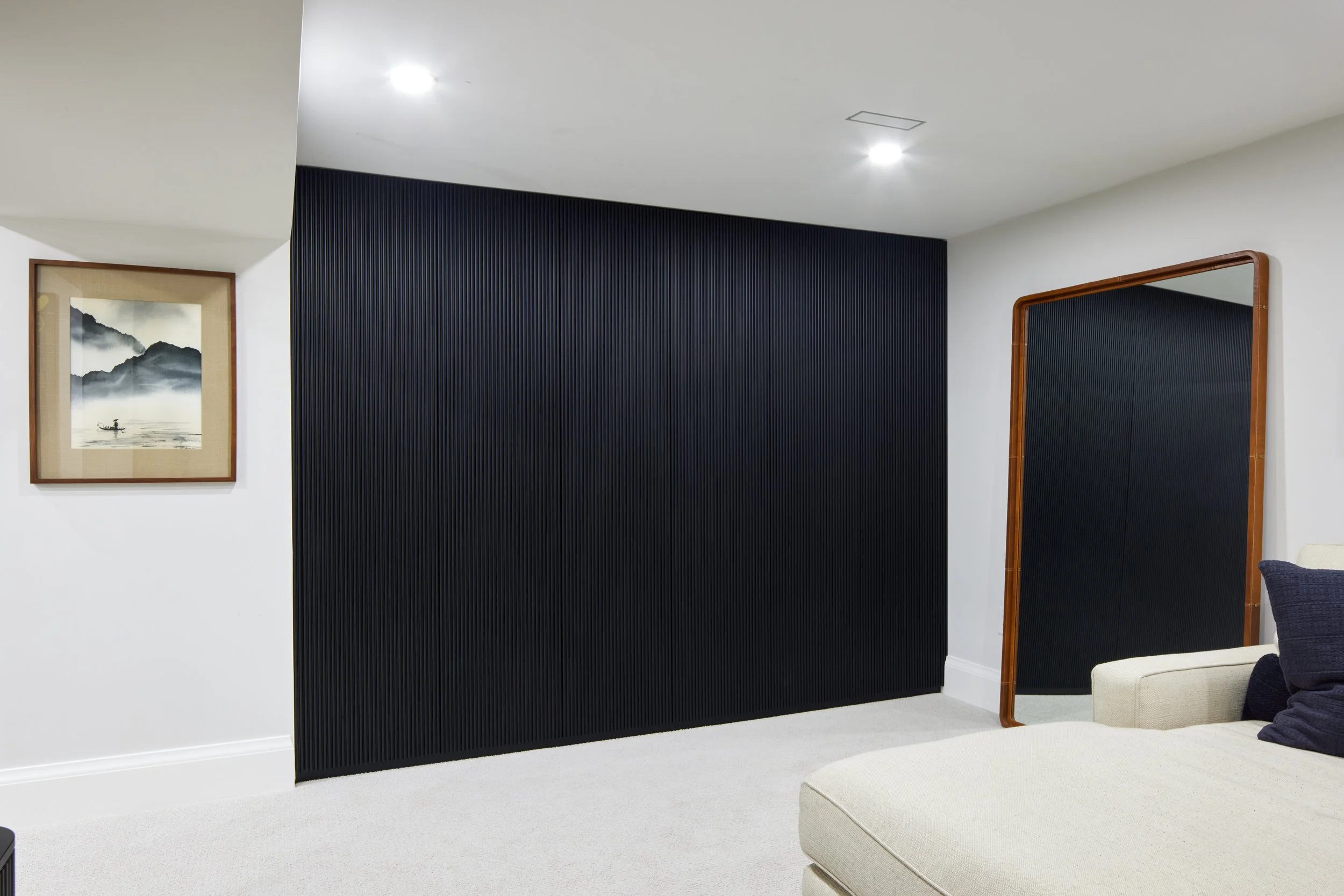 Custom closet cabinetry in matte black with minimalist handles, cabinet from floor to ceiling to maximize storage with smooth, clean lines design, custom closet with hidden door near me across Greater Toronto Area, Mississauga, Oakville.