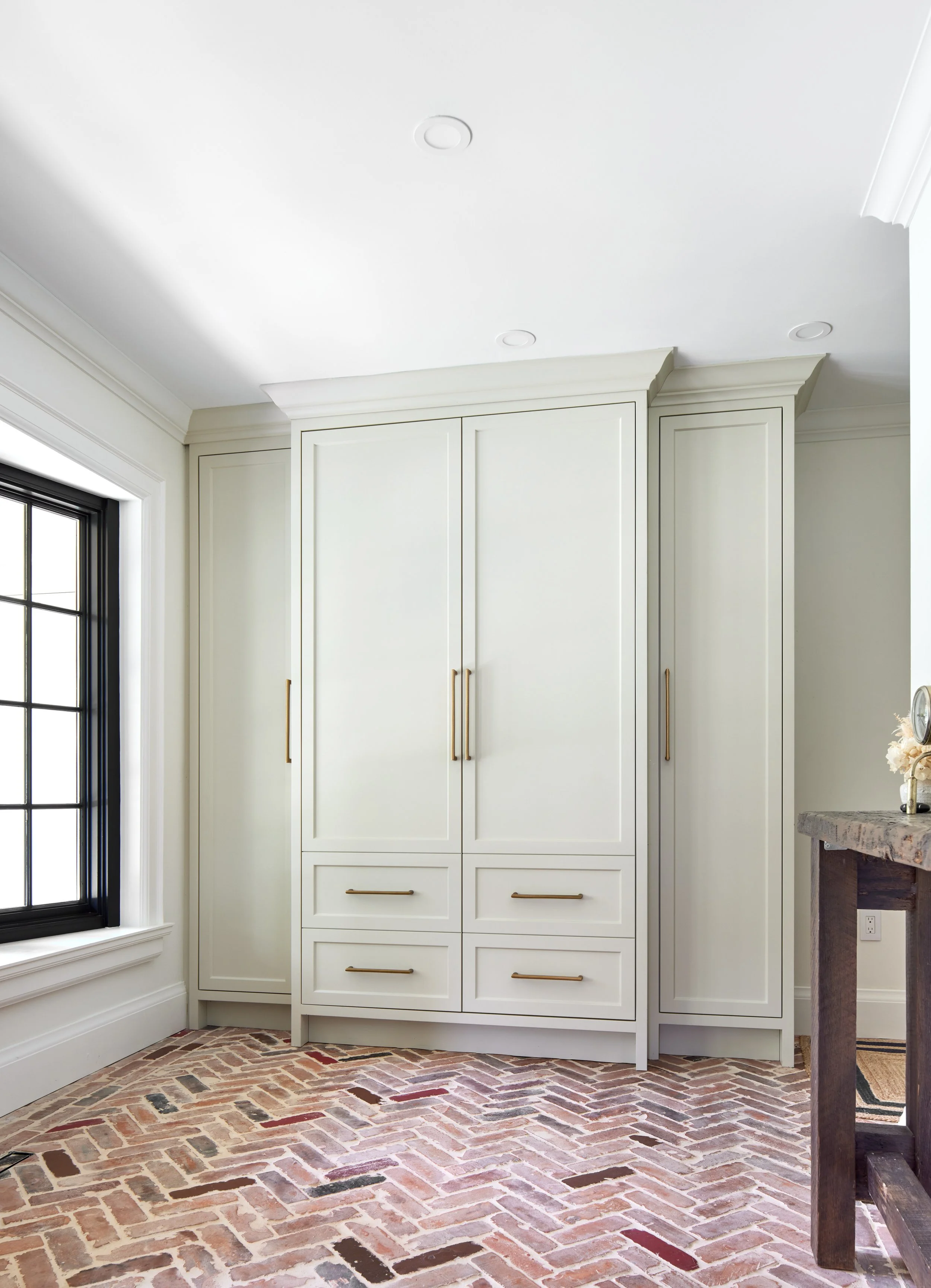 Elegant custom-designed foyer closet unit, showcasing color trends for 2024. Features ample storage with tall doors equipped with brushed gold handles, enhancing the sophisticated look. Provides a practical and welcoming entryway solution, ideal for 
