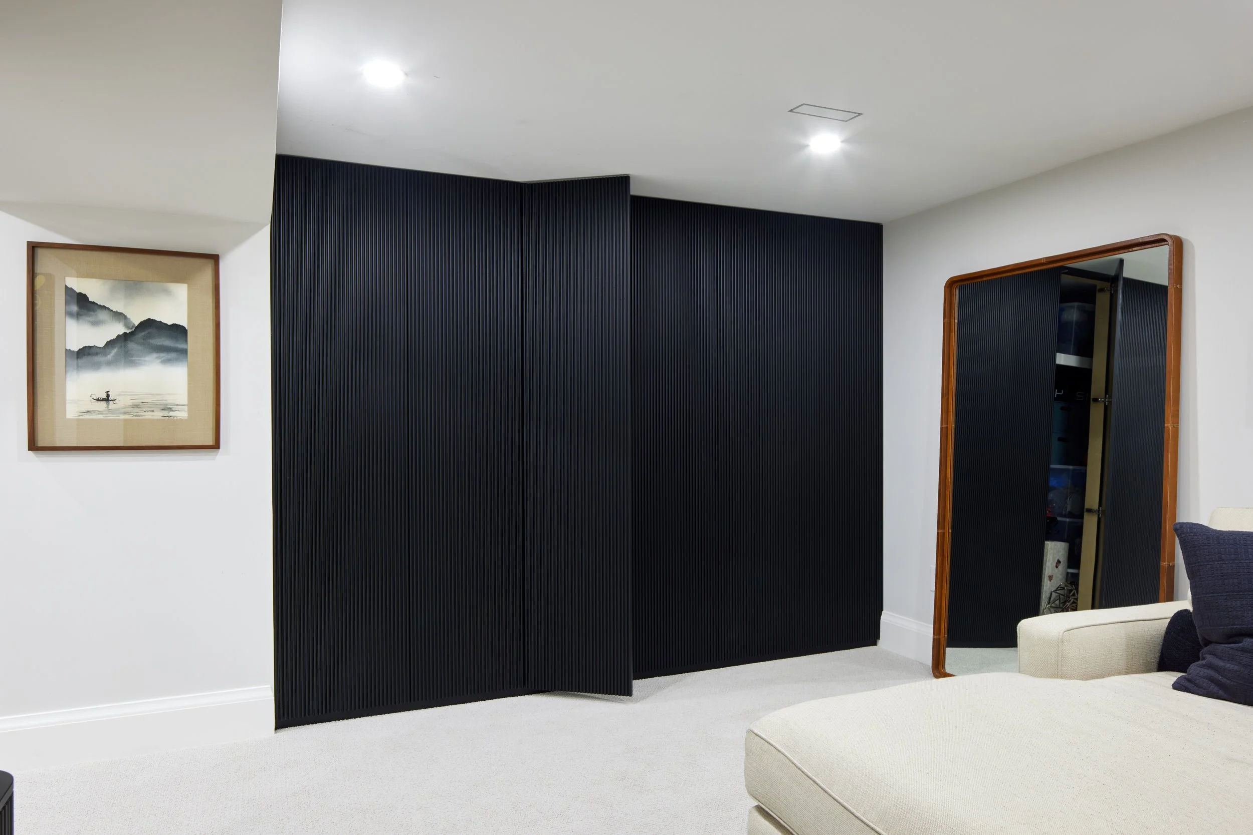 Custom closet cabinetry in matte black with minimalist handles, cabinet from floor to ceiling to maximize storage with smooth, clean lines design, custom closet with hidden door near me across Greater Toronto Area, Mississauga, Oakville.
