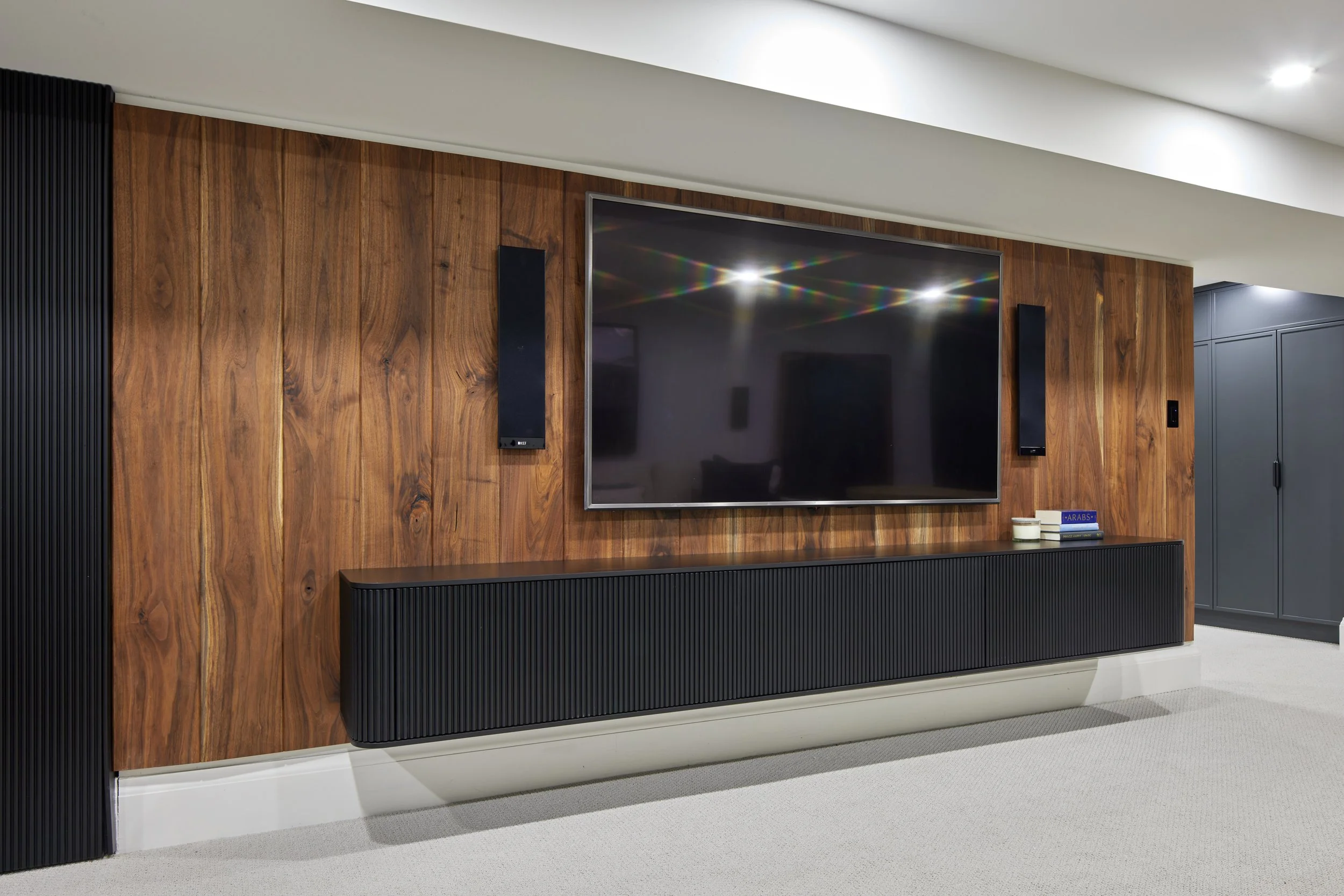 Custom closet cabinetry in matte black with minimalist handles, cabinet from floor to ceiling to maximize storage with smooth, clean lines design, custom closet with hidden door near me across Greater Toronto Area, Mississauga, Oakville.