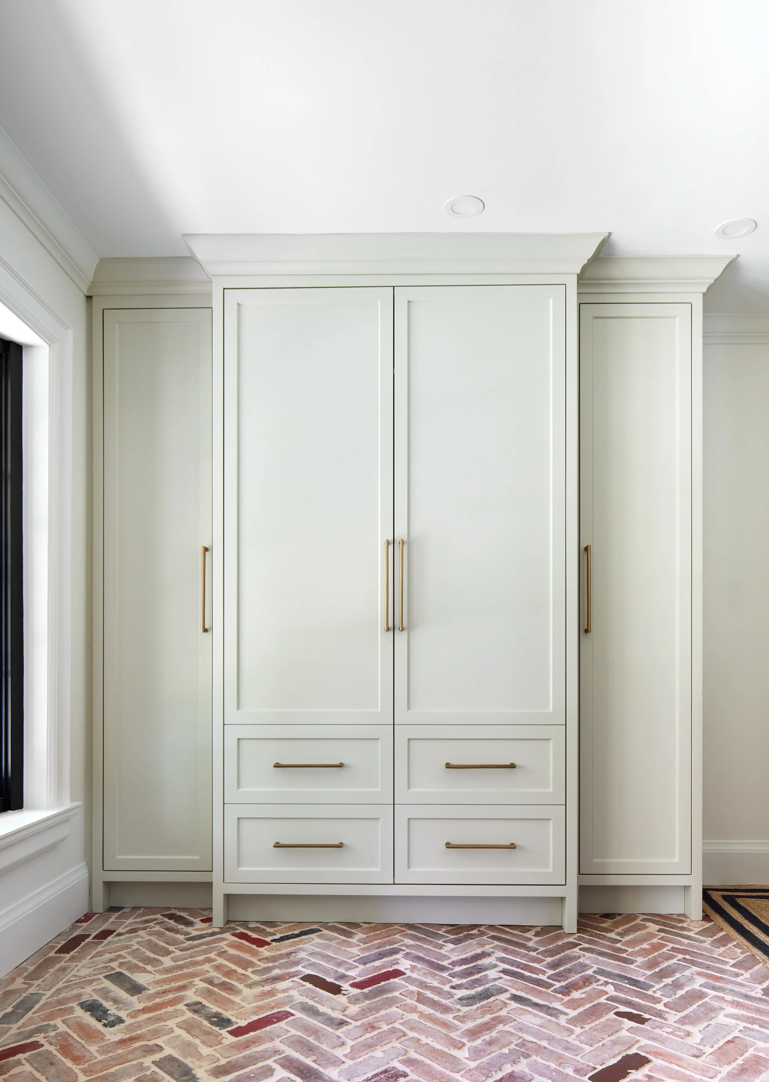 Elegant custom-designed foyer closet unit, showcasing color trends for 2024. Features ample storage with tall doors equipped with brushed gold handles, enhancing the sophisticated look. Provides a practical and welcoming entryway solution, ideal for 