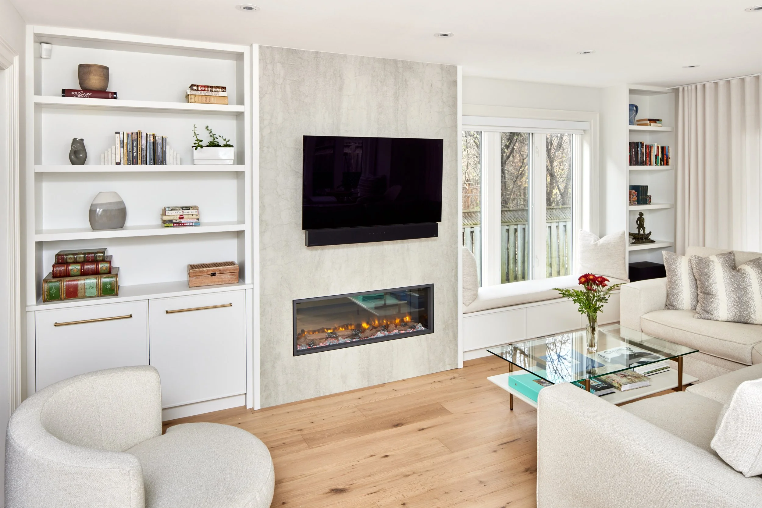 This cozy living room blends style with comfort, featuring a minimalist design with soft-toned sofas perfect for relaxing or hosting guests. A sleek, built-in fireplace adds a touch of elegance, creating a warm and inviting atmosphere.