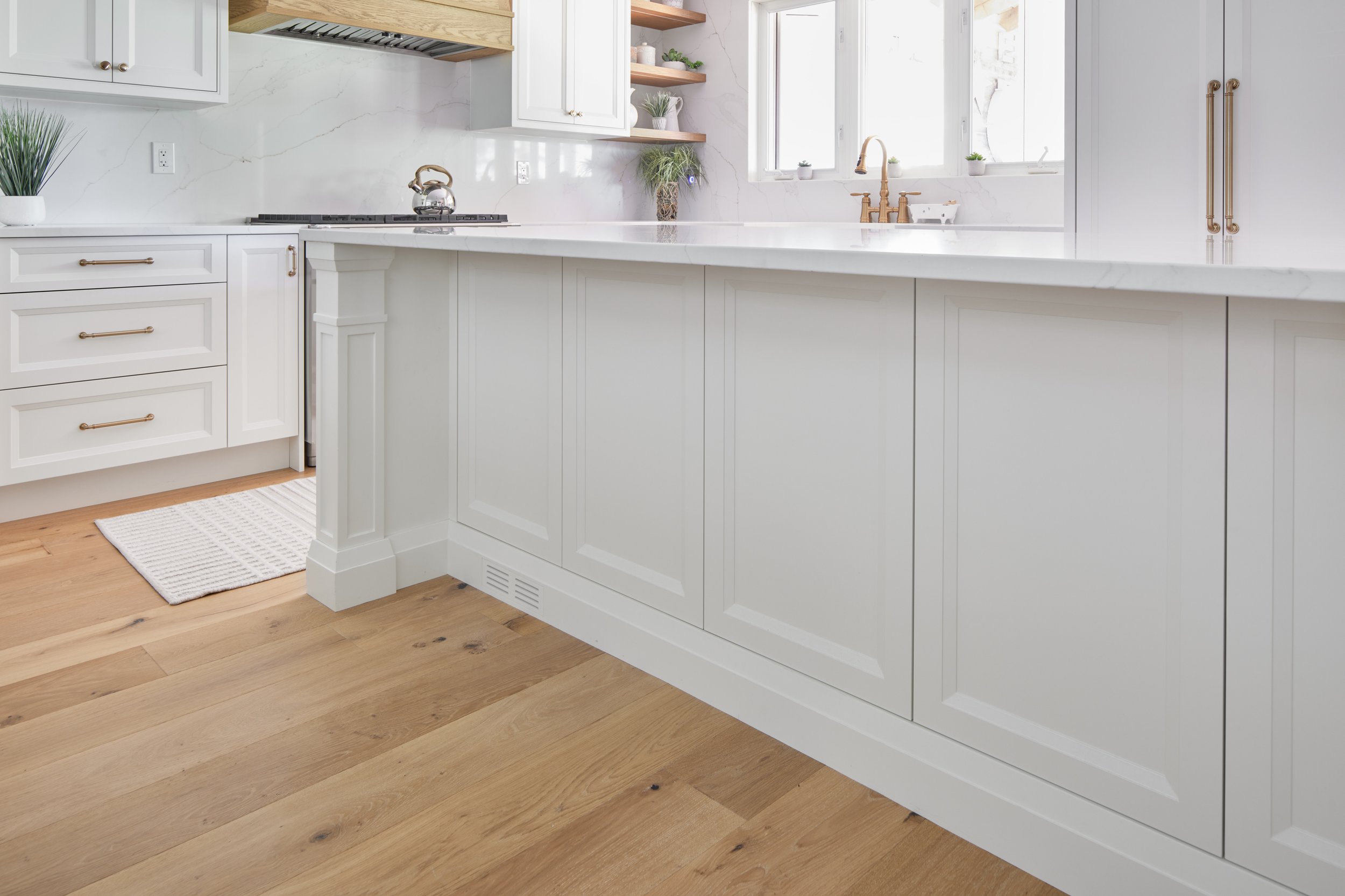 Modern custom kitchen features high-end brass fixtures and an undermount sink. High-end custom modern kitchen in Mississauga, Oakville, and Toronto, Ontario. Features trends color for 2024, luxurious gold hardware, a marble countertop, an elegant kit