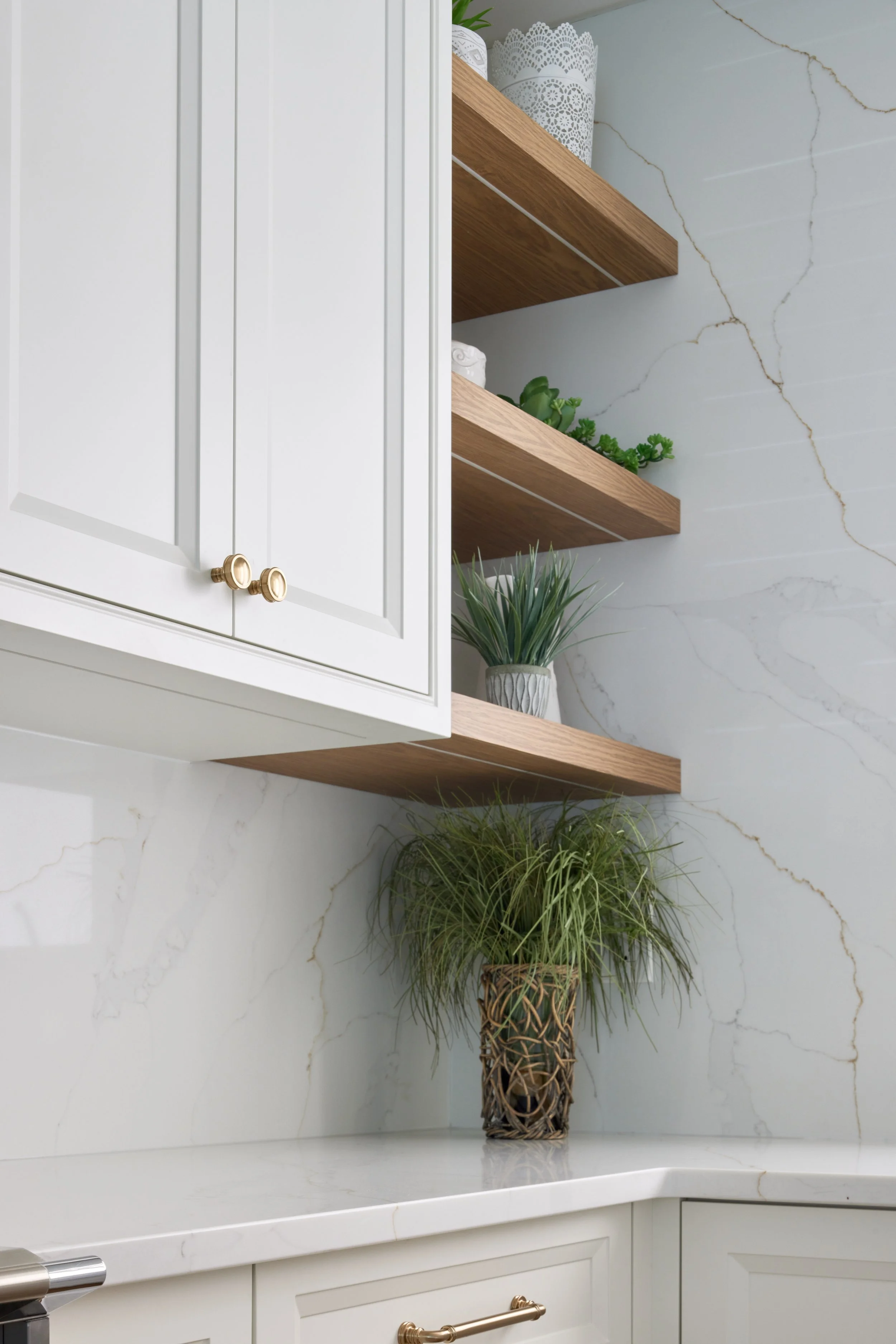 Modern custom kitchen features high-end brass fixtures and an undermount sink. High-end custom modern kitchen in Mississauga, Oakville, and Toronto, Ontario. Features trends color for 2024, luxurious gold hardware, a marble countertop, an elegant kit