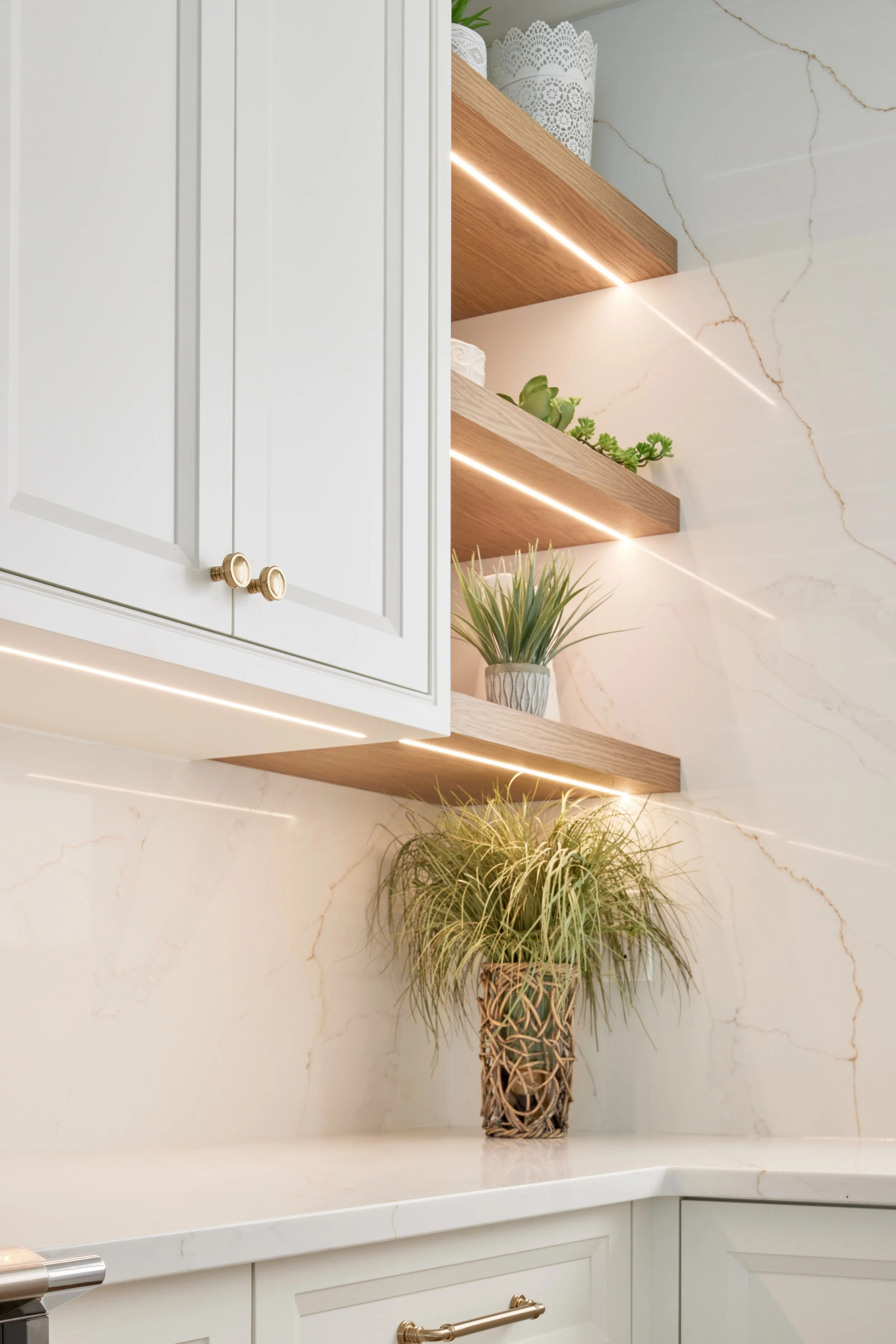 Modern custom kitchen features high-end brass fixtures and an undermount sink. High-end custom modern kitchen in Mississauga, Oakville, and Toronto, Ontario. Features trends color for 2024, luxurious gold hardware, a marble countertop, an elegant kit