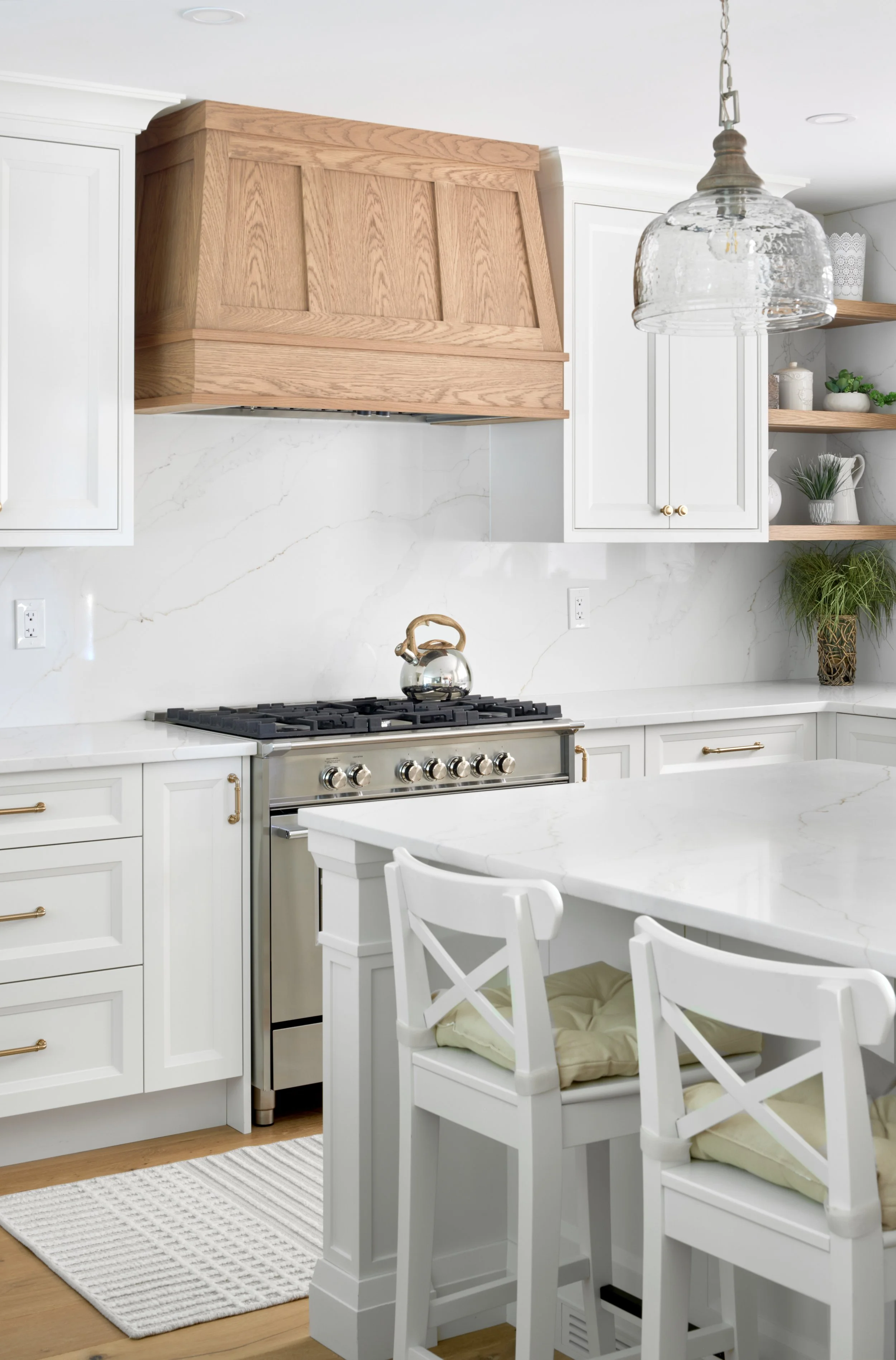 Modern custom kitchen features high-end brass fixtures and an undermount sink. High-end custom modern kitchen in Mississauga, Oakville, and Toronto, Ontario. Features trends color for 2024, luxurious gold hardware, a marble countertop, an elegant kit