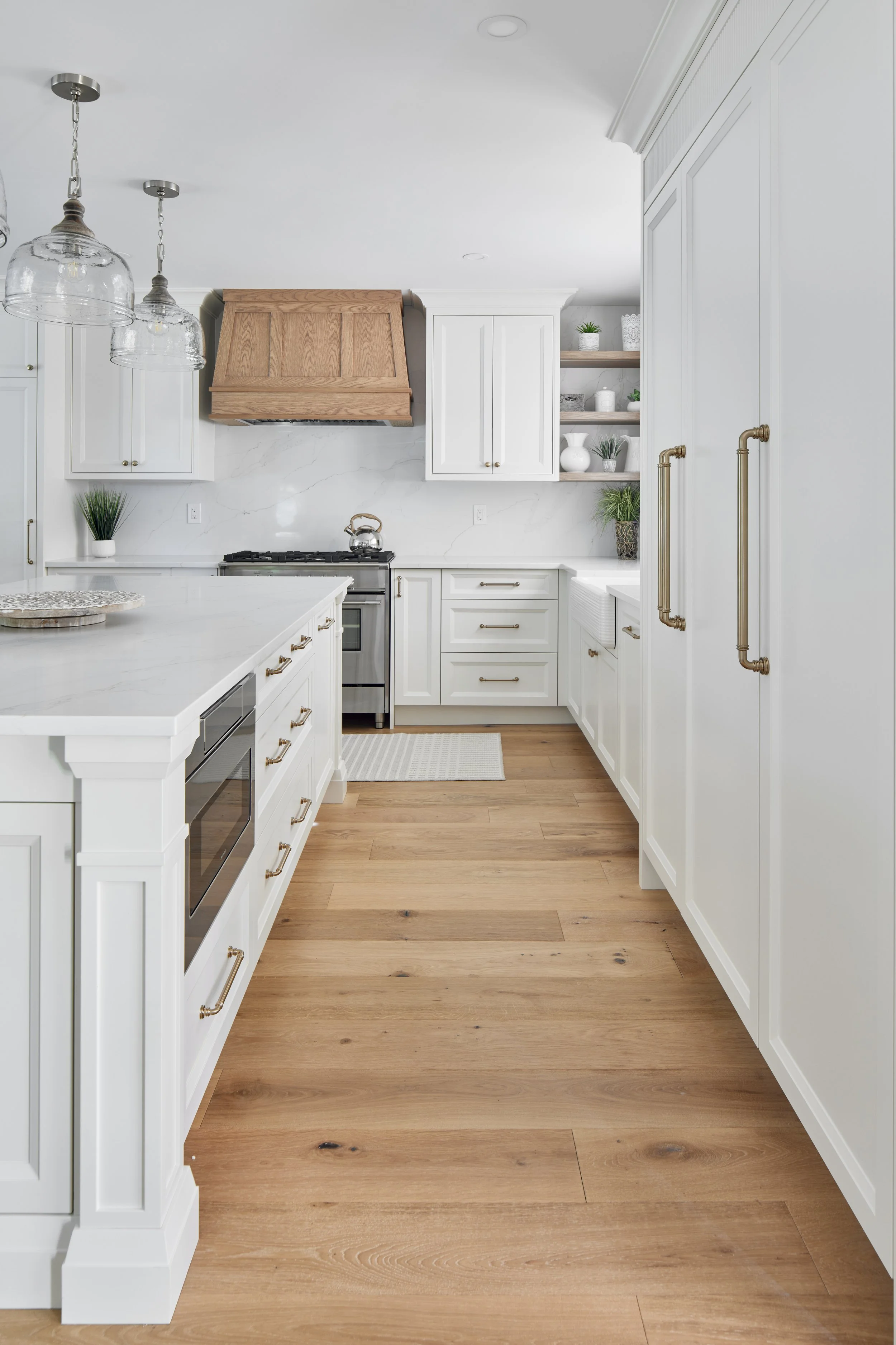 Modern custom kitchen features high-end brass fixtures and an undermount sink. High-end custom modern kitchen in Mississauga, Oakville, and Toronto, Ontario. Features trends color for 2024, luxurious gold hardware, a marble countertop, an elegant kit