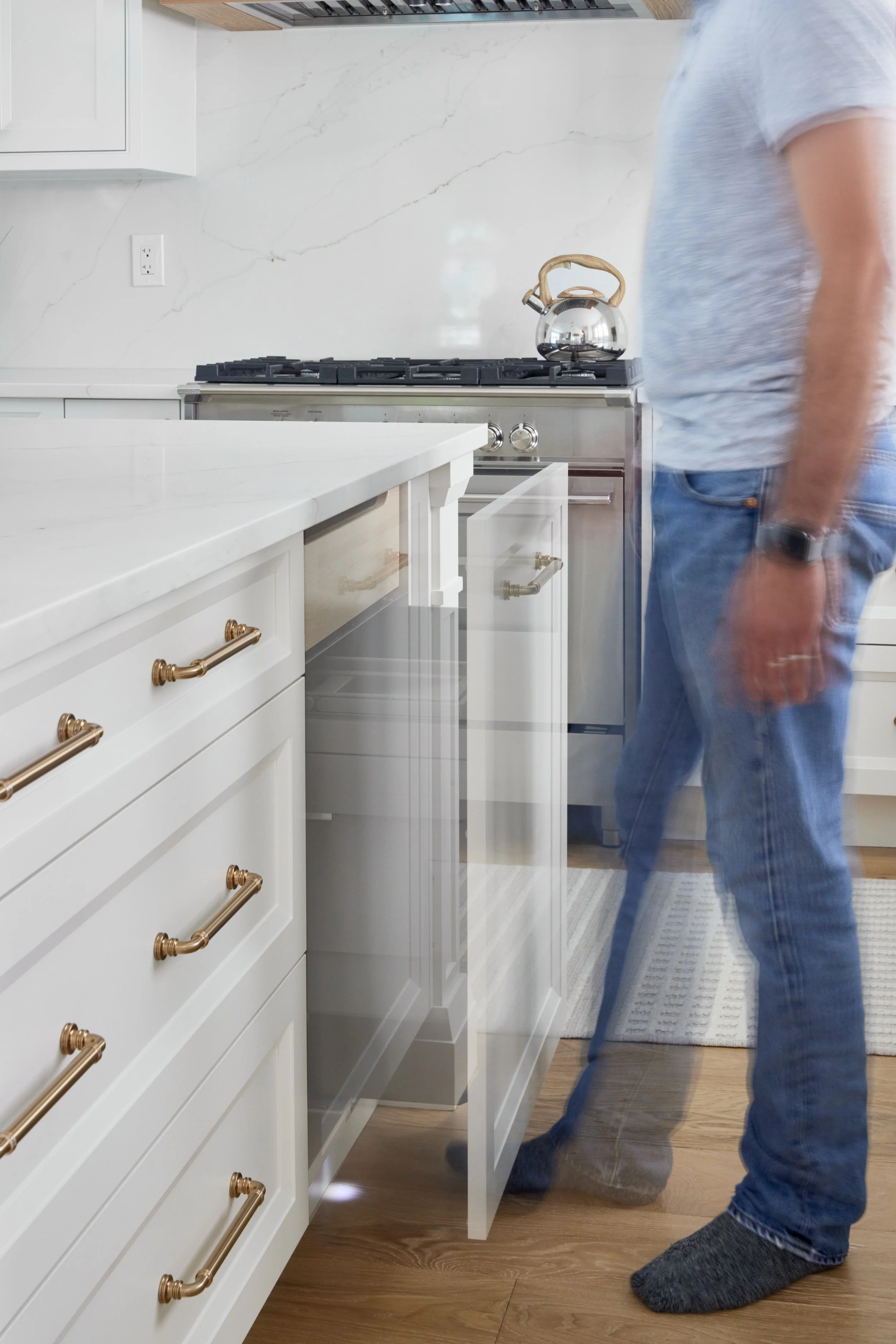 Modern custom kitchen features high-end brass fixtures and an undermount sink. High-end custom modern kitchen in Mississauga, Oakville, and Toronto, Ontario. Features trends color for 2024, luxurious gold hardware, a marble countertop, an elegant kit