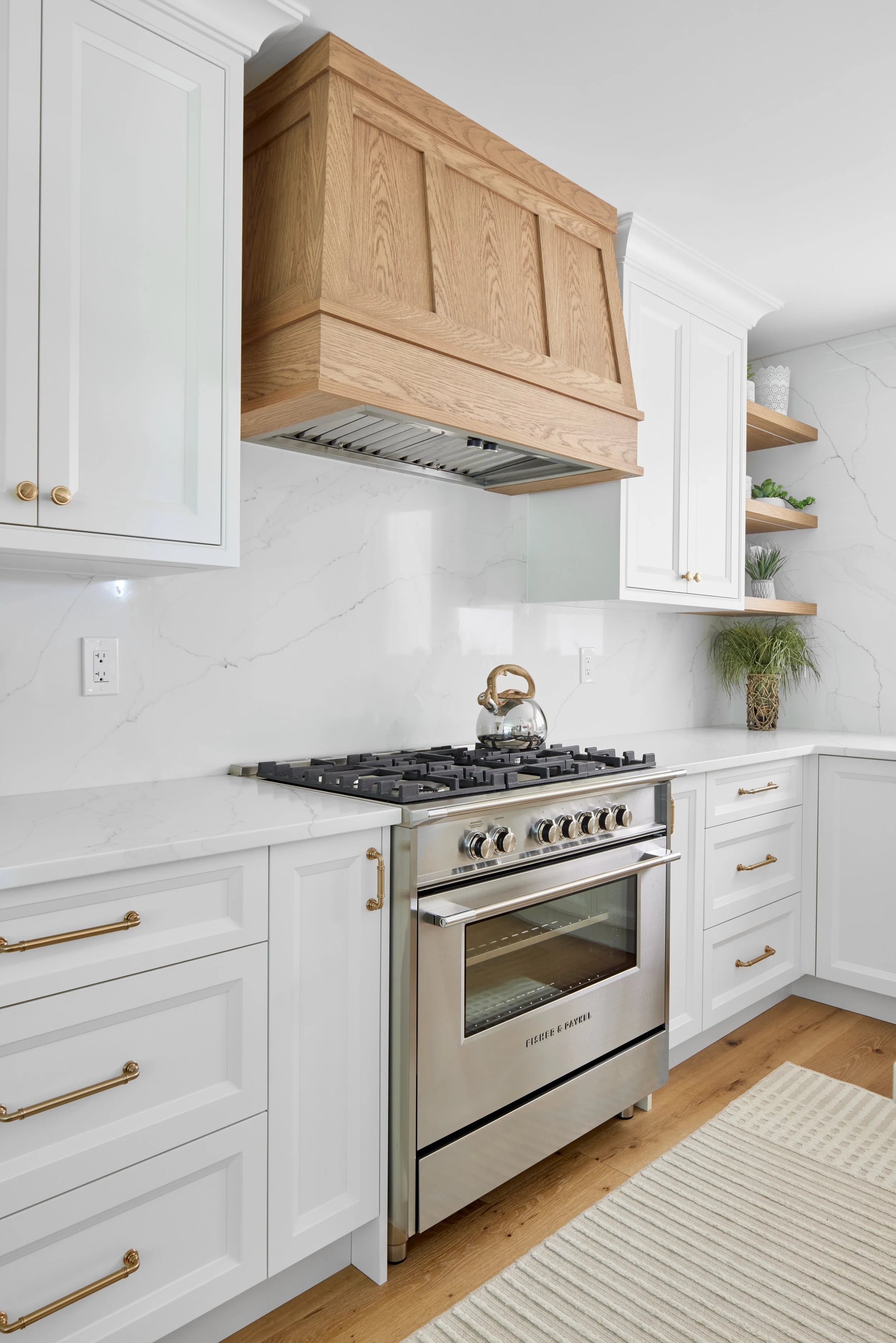 Modern custom kitchen features high-end brass fixtures and an undermount sink. High-end custom modern kitchen in Mississauga, Oakville, and Toronto, Ontario. Features trends color for 2024, luxurious gold hardware, a marble countertop, an elegant kit