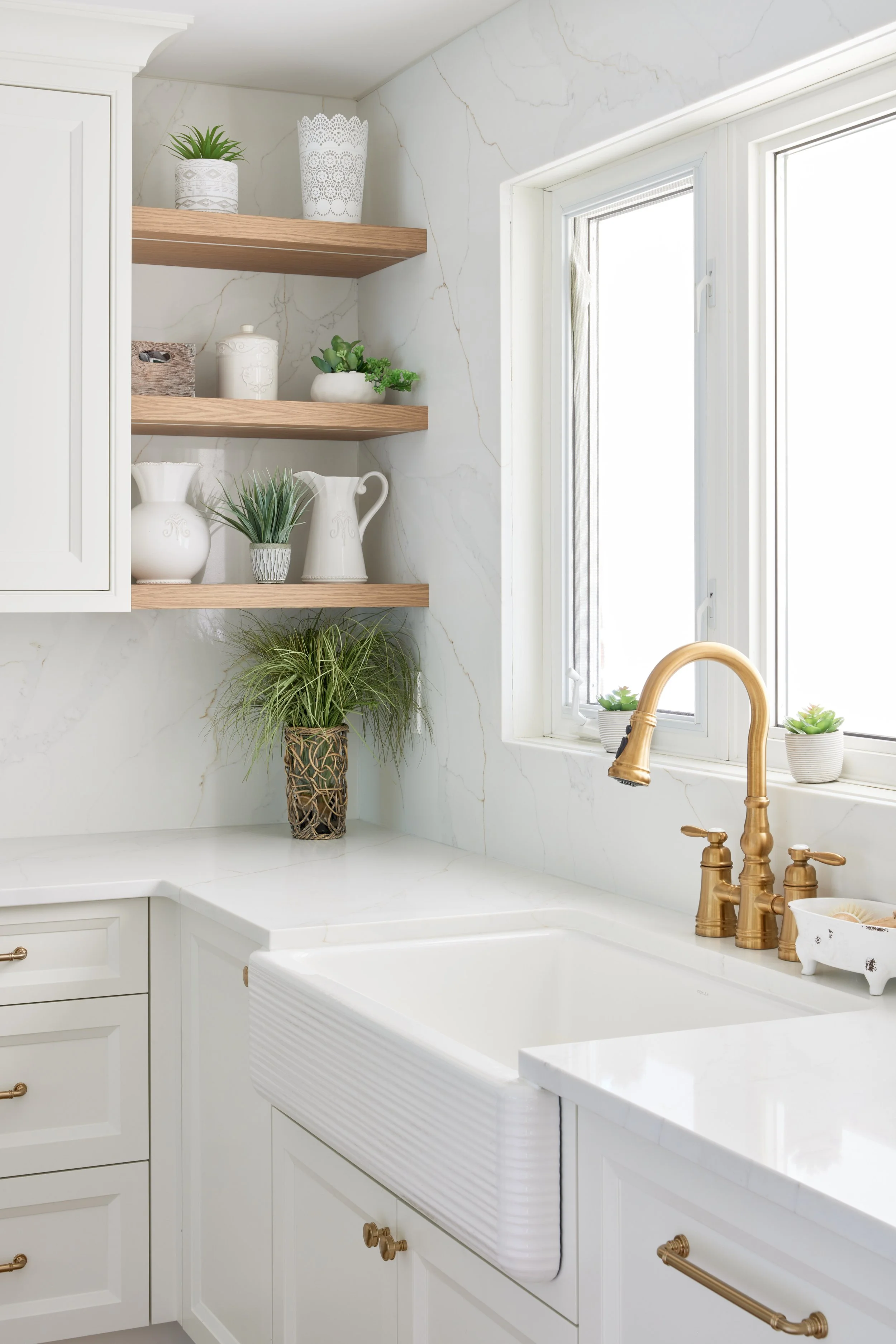 Modern custom kitchen features high-end brass fixtures and an undermount sink. High-end custom modern kitchen in Mississauga, Oakville, and Toronto, Ontario. Features trends color for 2024, luxurious gold hardware, a marble countertop, an elegant kit