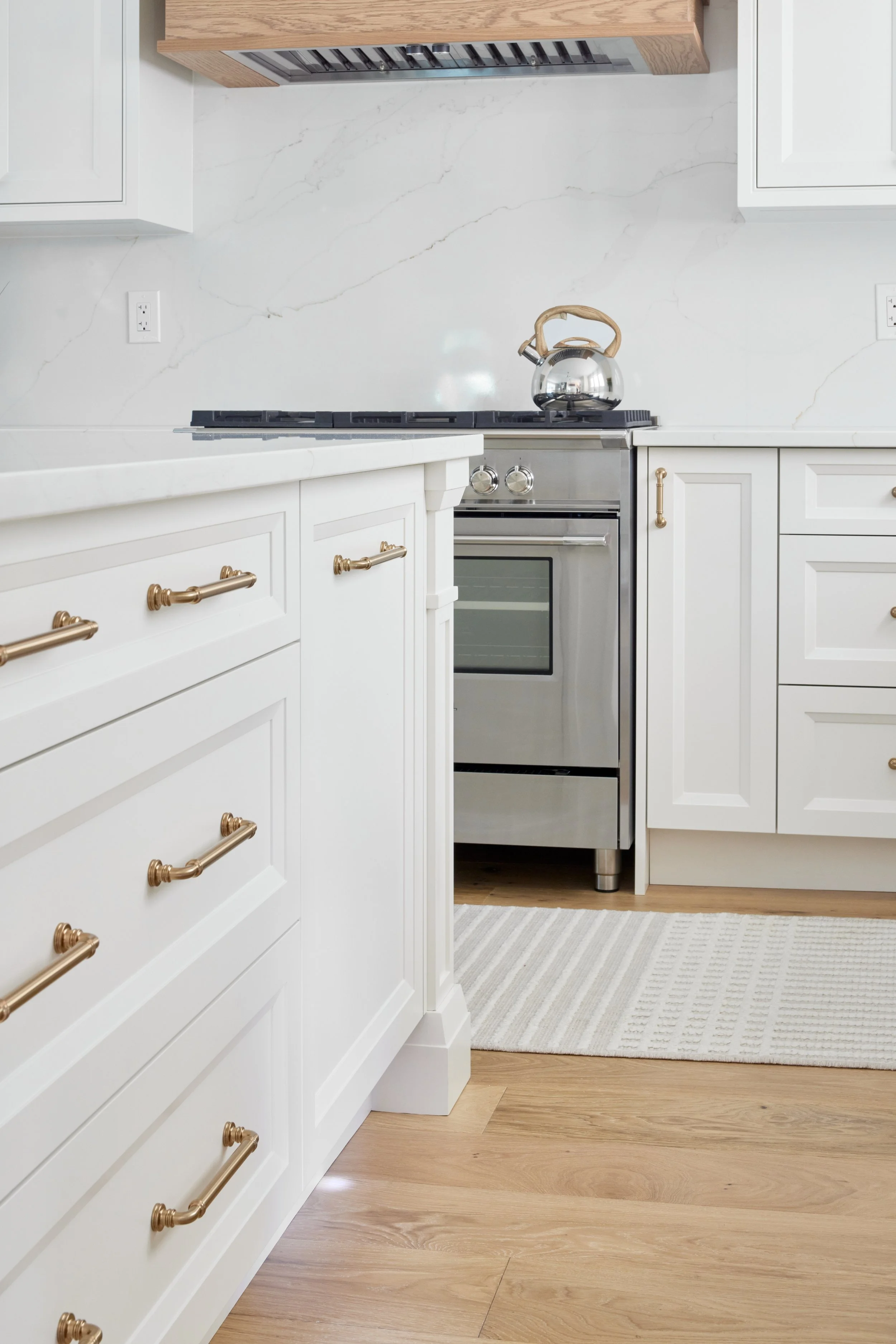 Modern custom kitchen features high-end brass fixtures and an undermount sink. High-end custom modern kitchen in Mississauga, Oakville, and Toronto, Ontario. Features trends color for 2024, luxurious gold hardware, a marble countertop, an elegant kit