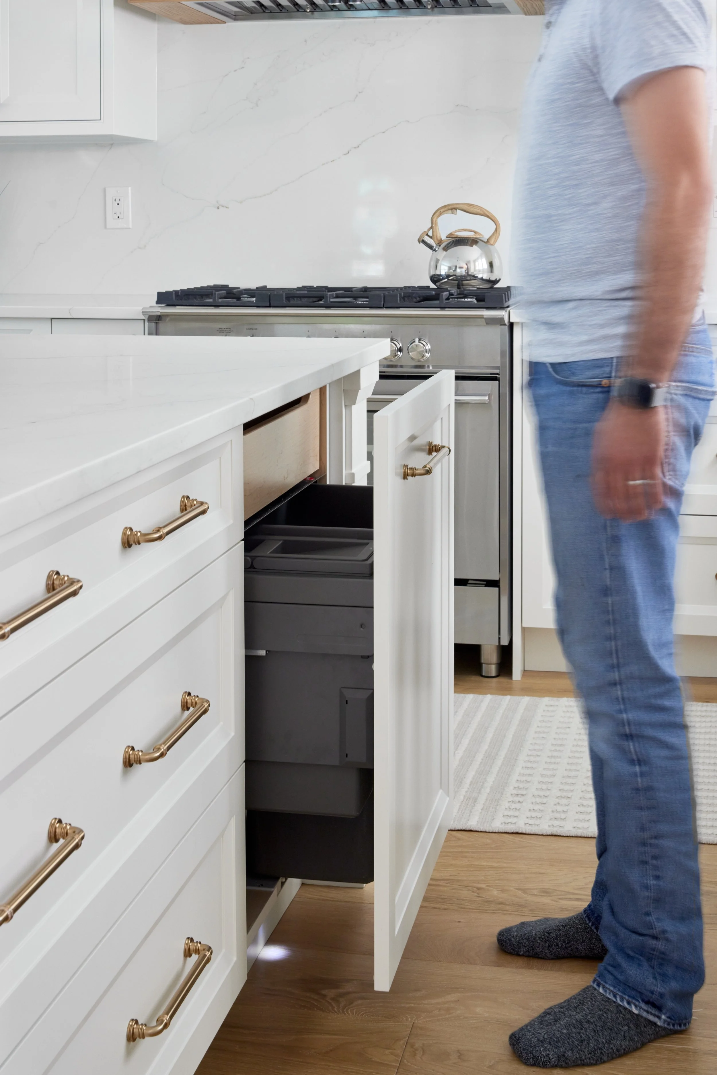 Modern custom kitchen features high-end brass fixtures and an undermount sink. High-end custom modern kitchen in Mississauga, Oakville, and Toronto, Ontario. Features trends color for 2024, luxurious gold hardware, a marble countertop, an elegant kit