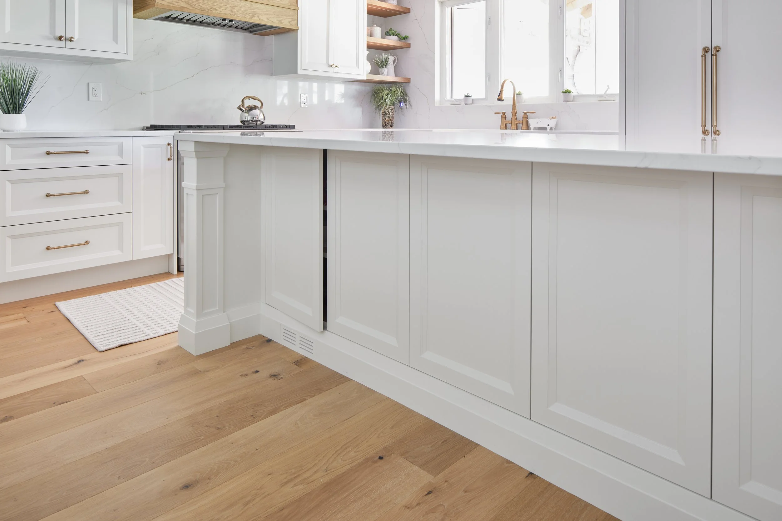 Modern custom kitchen features high-end brass fixtures and an undermount sink. High-end custom modern kitchen in Mississauga, Oakville, and Toronto, Ontario. Features trends color for 2024, luxurious gold hardware, a marble countertop, an elegant kit
