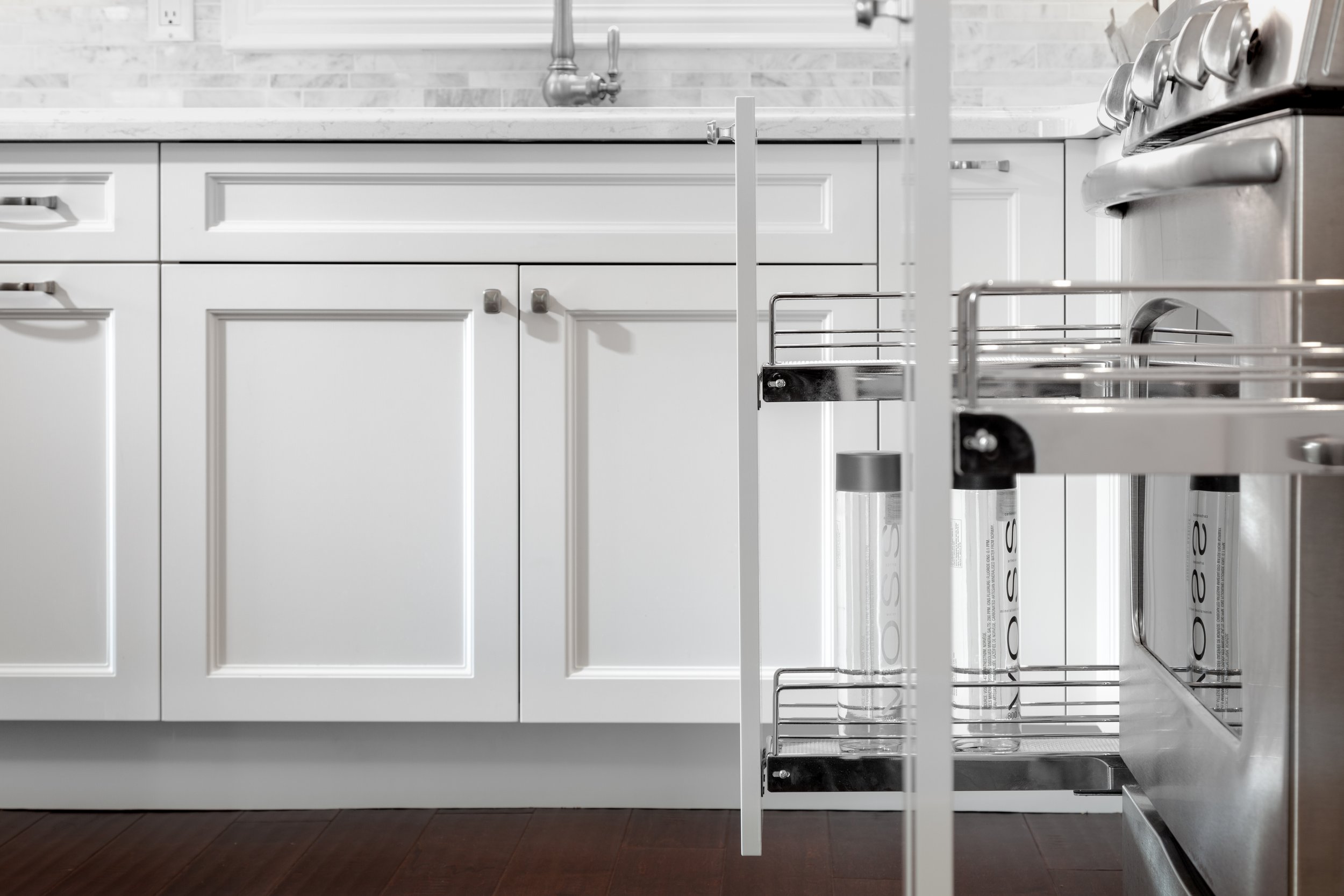 A kitchen cabinet with a pull-out spice rack and a stainless steel stove.