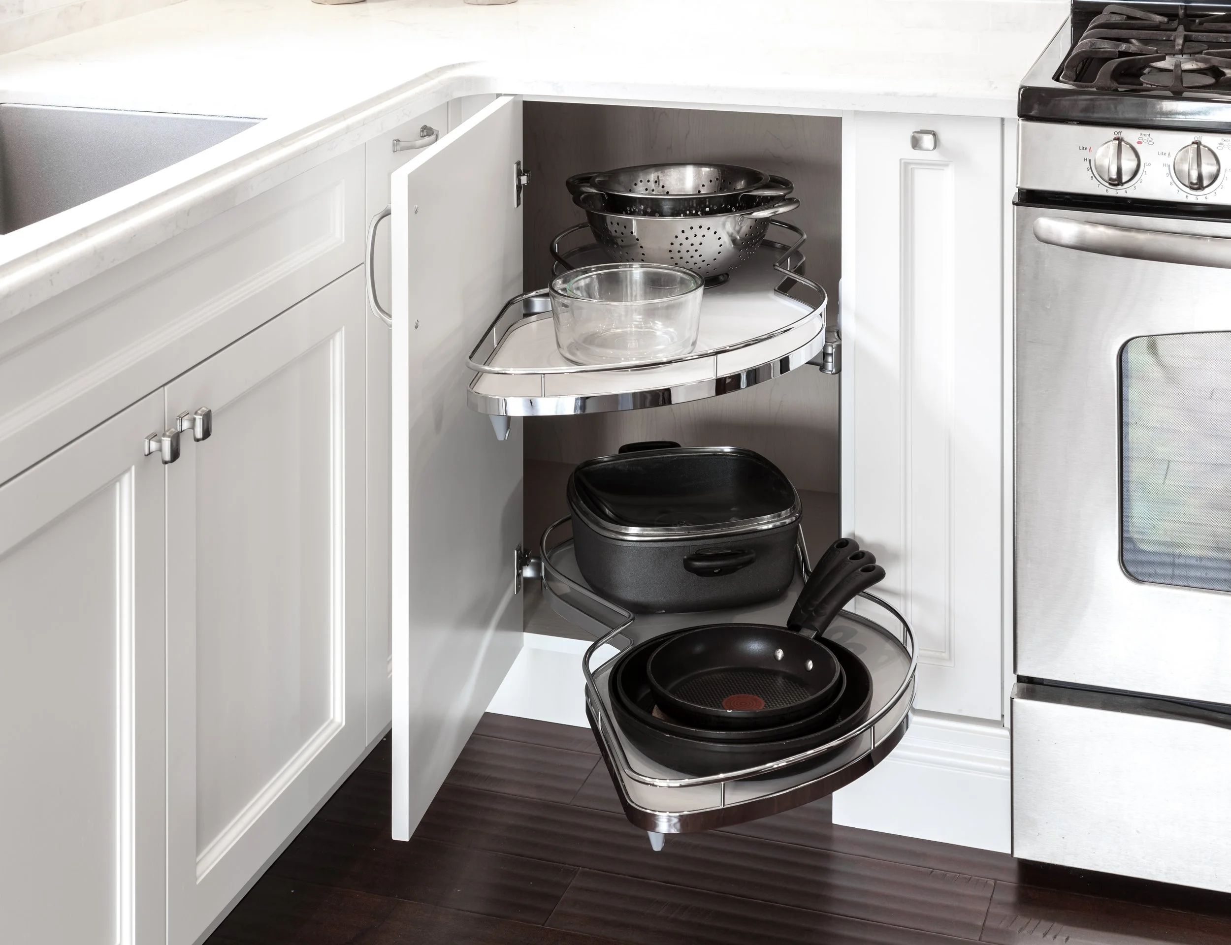 Kitchen cabinet with pull-out wire racks holding pots, pans, and bowls.