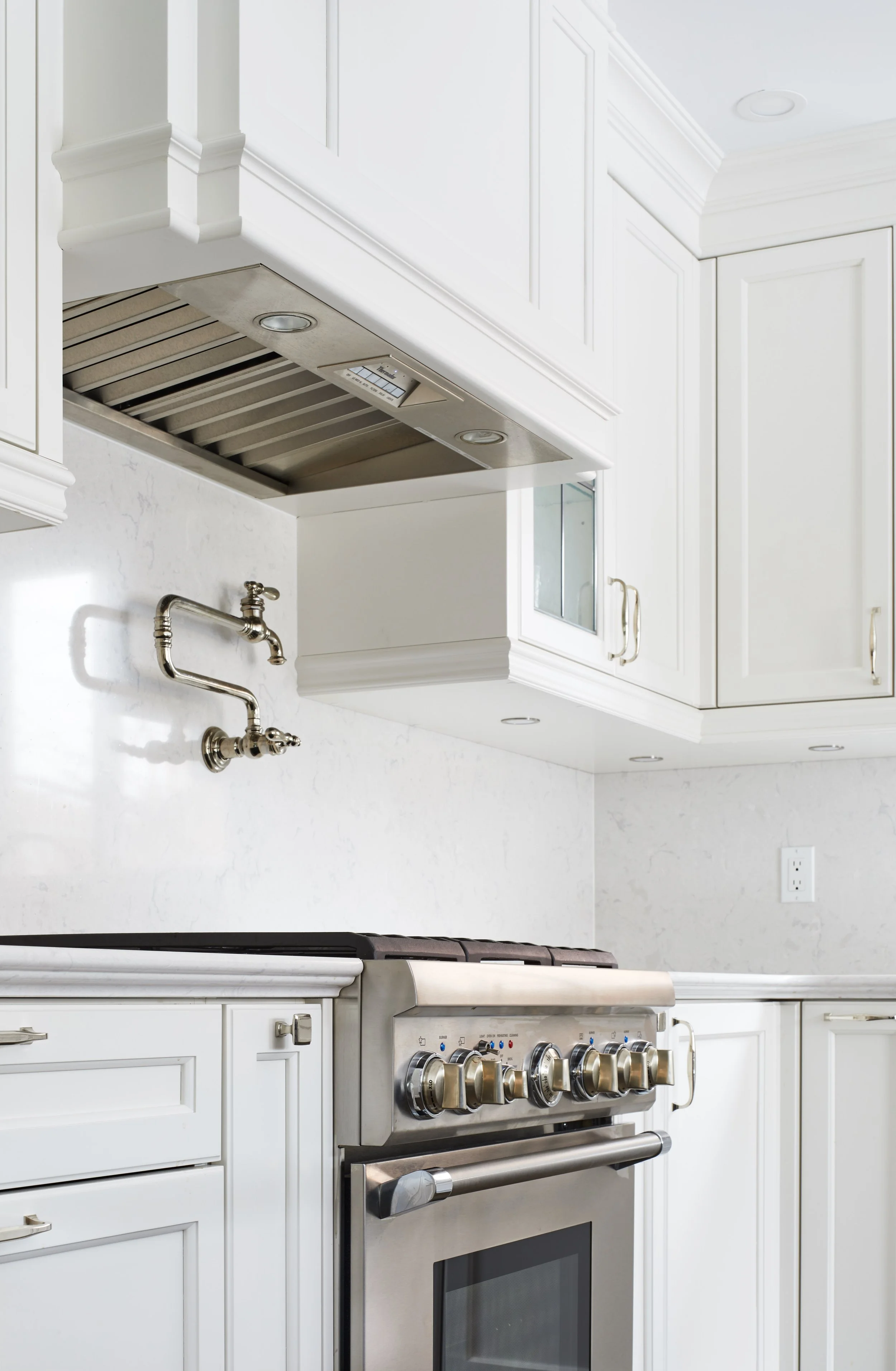 At Seif Designs, we offer top-quality kitchen renovation services around the GTA, Mississauga, Oakville. This traditional kitchen showcases custom white cabinetry with classic detailing and a bold blue island as the focal point. The island features i