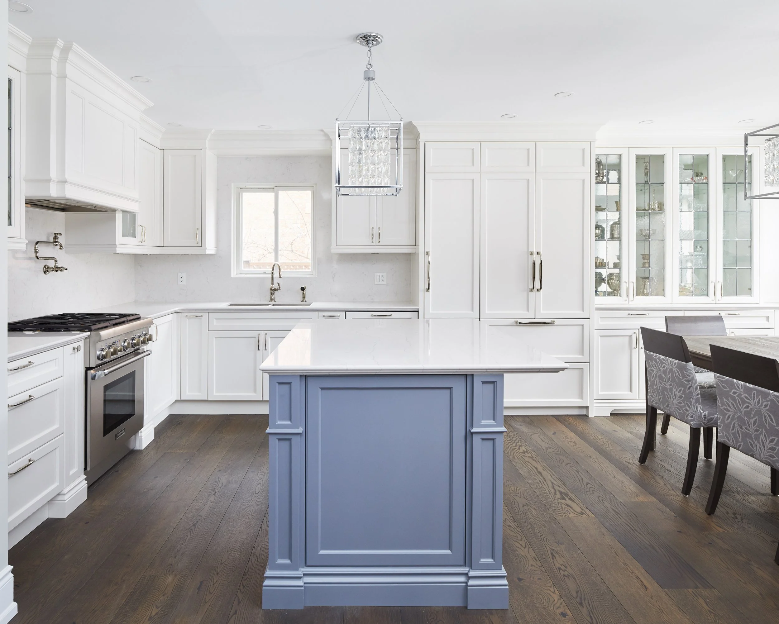 At Seif Designs, we offer top-quality kitchen renovation services around the GTA, Mississauga, Oakville. This traditional kitchen showcases custom white cabinetry with classic detailing and a bold blue island as the focal point. The island features i