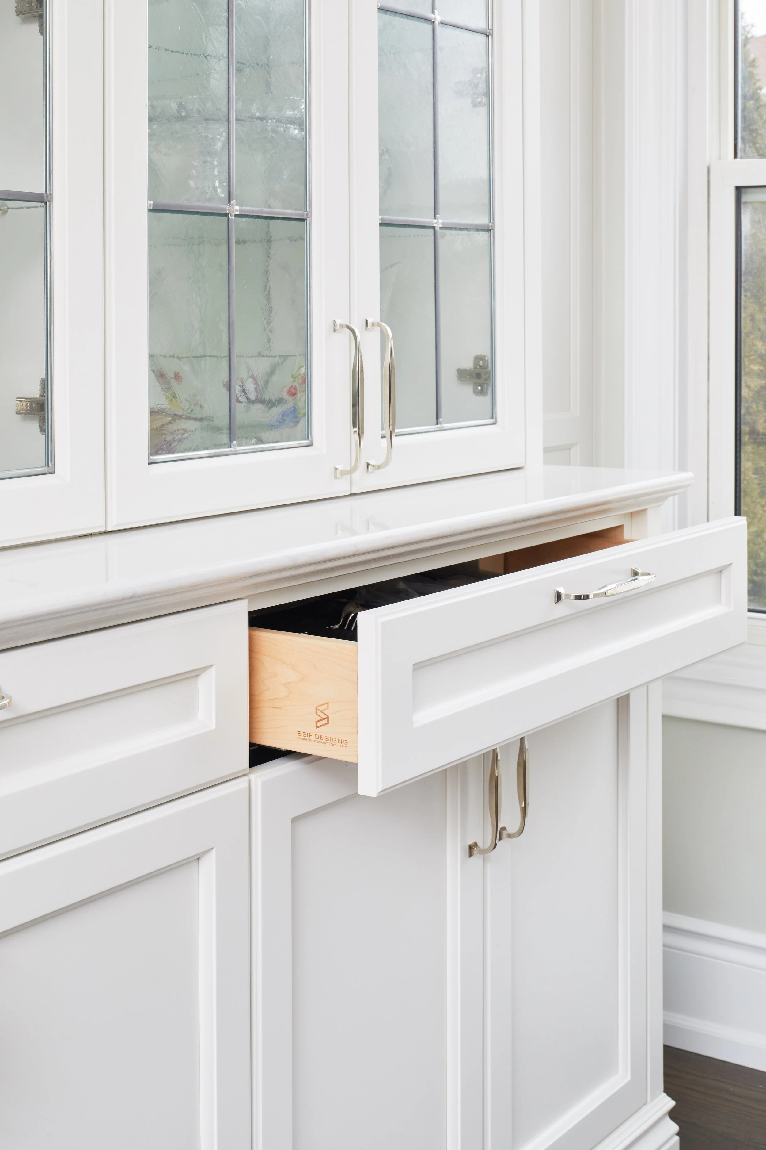 At Seif Designs, we offer top-quality kitchen renovation services around the GTA, Mississauga, Oakville. This traditional kitchen showcases custom white cabinetry with classic detailing and a bold blue island as the focal point. The island features i